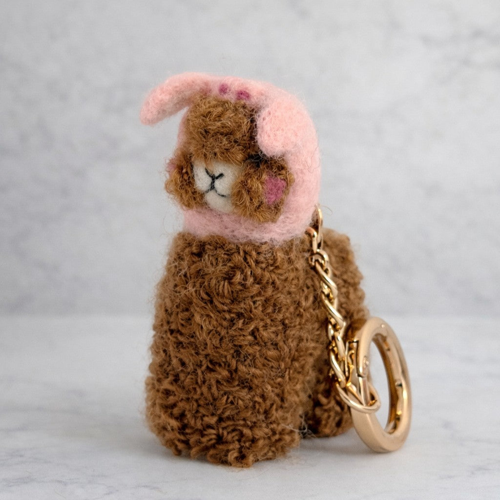 Handmade needle felted alpaca keychain wearing a pig hat