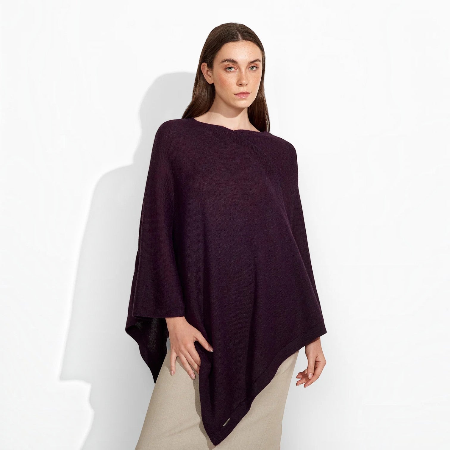 Front view of a woman wearing the Almendra Baby Alpaca poncho in deep plum