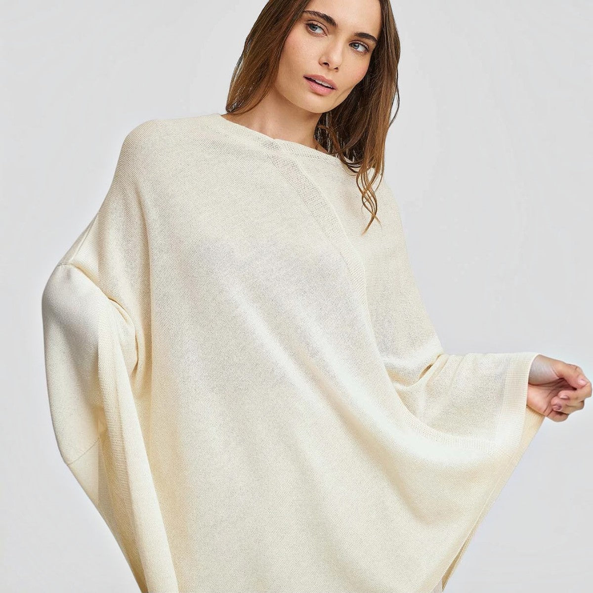 Female model wearing the Almendra ivory alpaca poncho