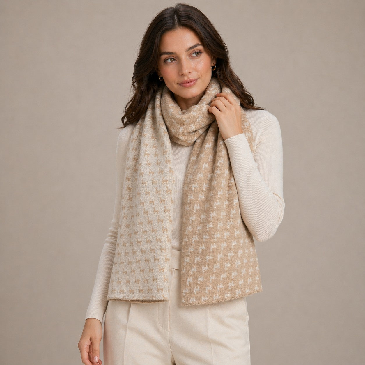 Woman wearing warm alpaca scarf with alpaca design detail in camel and cream