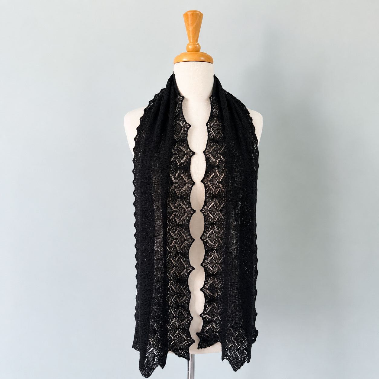 Black baby alpaca lace knit scarf displayed on a mannequin, featuring intricate openwork detailing