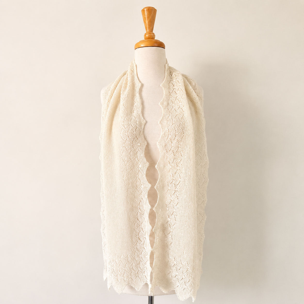 Ecru baby alpaca lace knit scarf displayed on a mannequin, showcasing its delicate lightweight texture