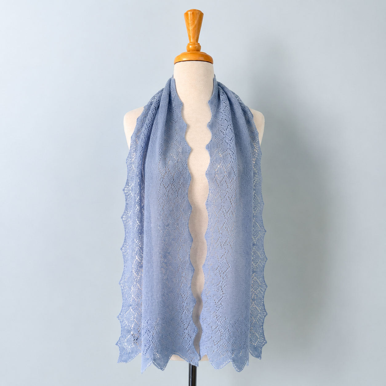 Pale blue baby alpaca lace scarf displayed on a mannequin with elegant openwork knit detailing
