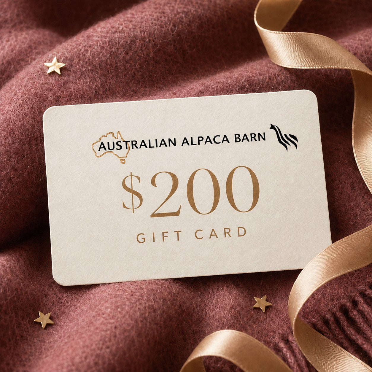 Australian Alpaca Barn $200 gift card presented on berry alpaca fabric with an ivory card, champagne ribbon and gold stars