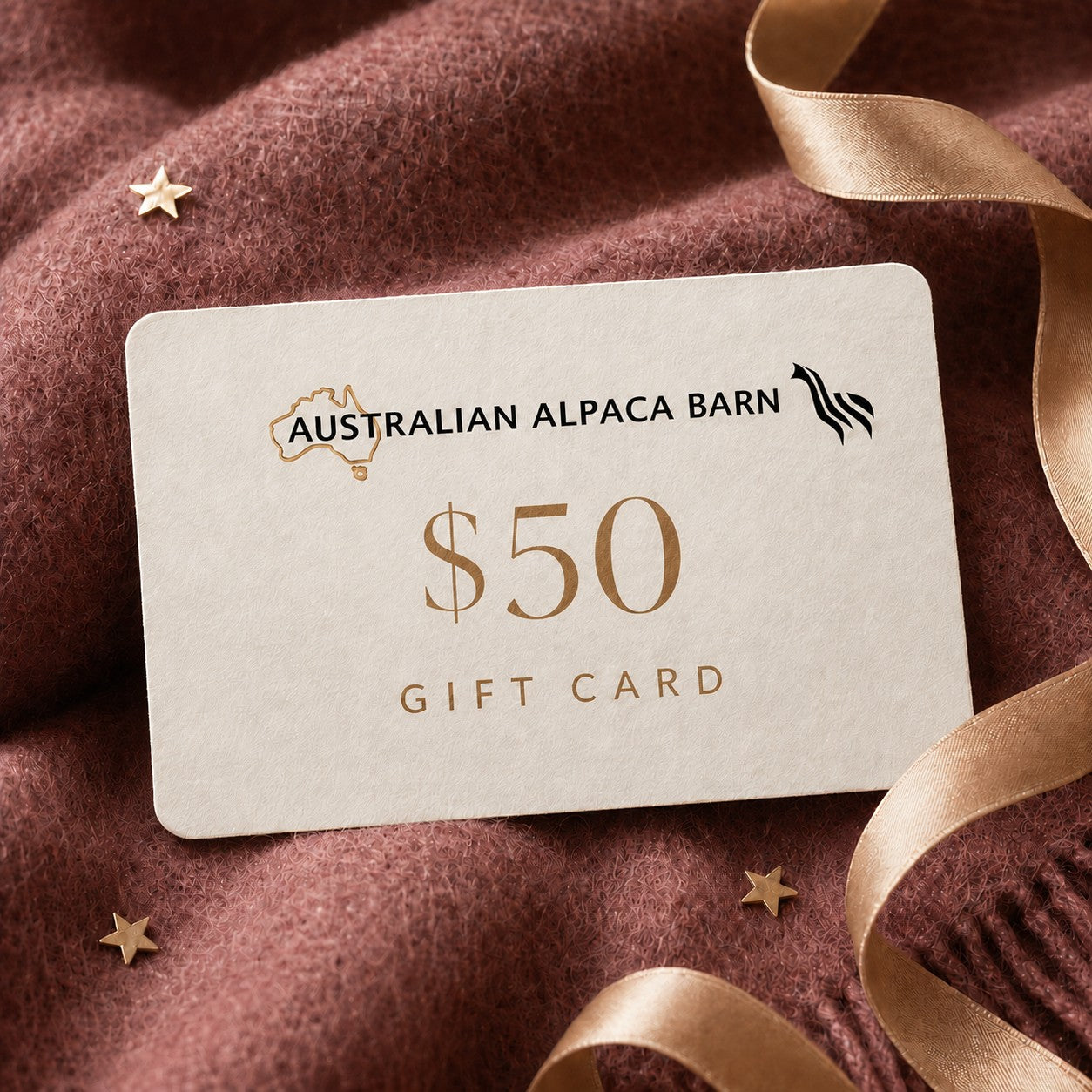 Australian Alpaca Barn $50 gift card presented on berry alpaca fabric with an ivory card, champagne ribbon and gold stars