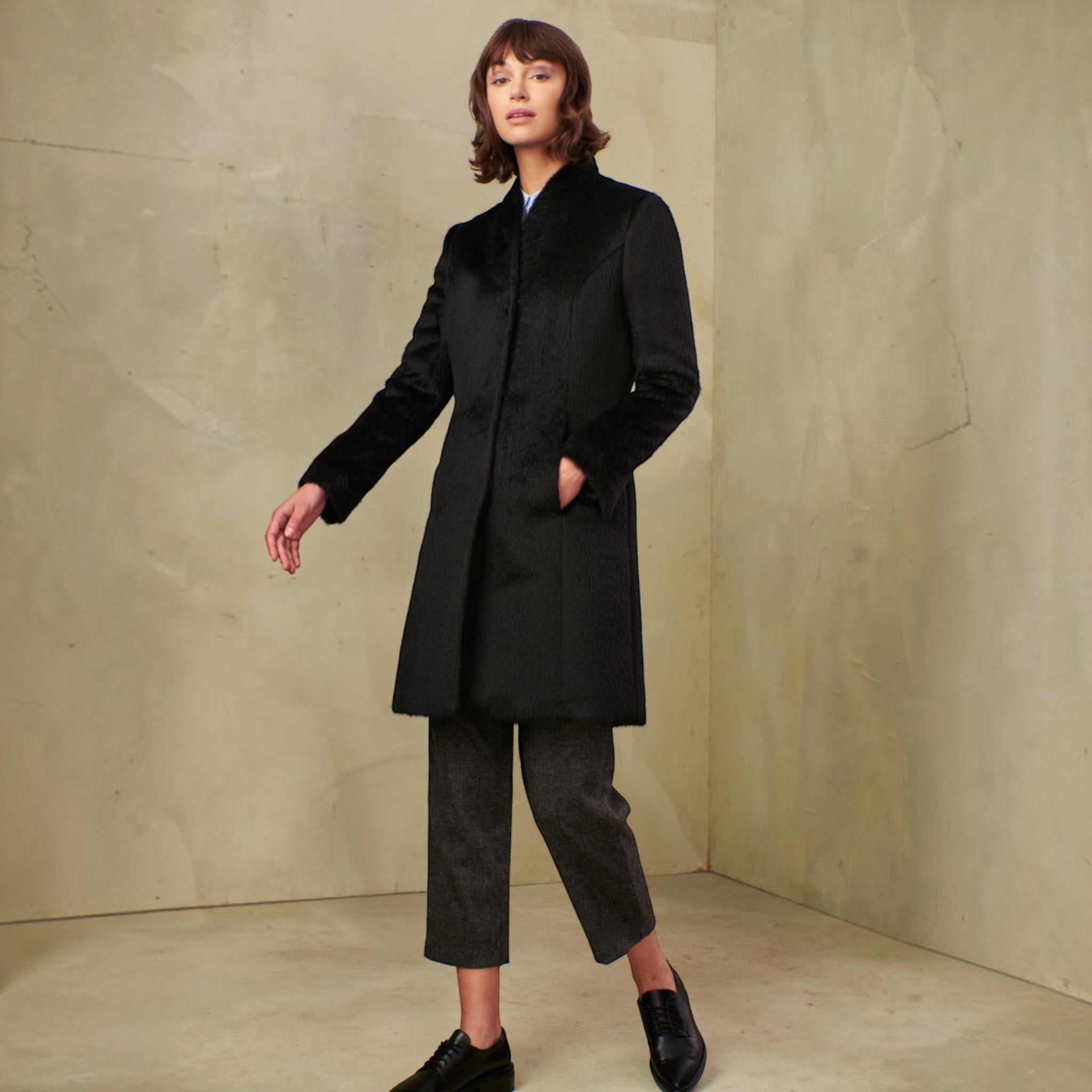 Woman wearing the Theory black Suri alpaca coat with tailored longline silhouette