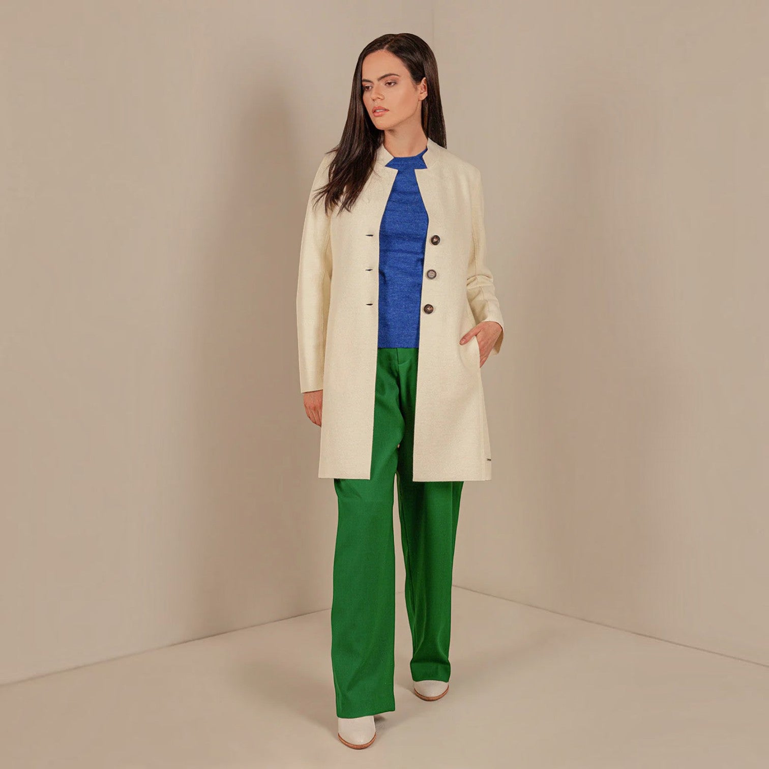 Women’s ecru mid-length alpaca coat styled with green trousers