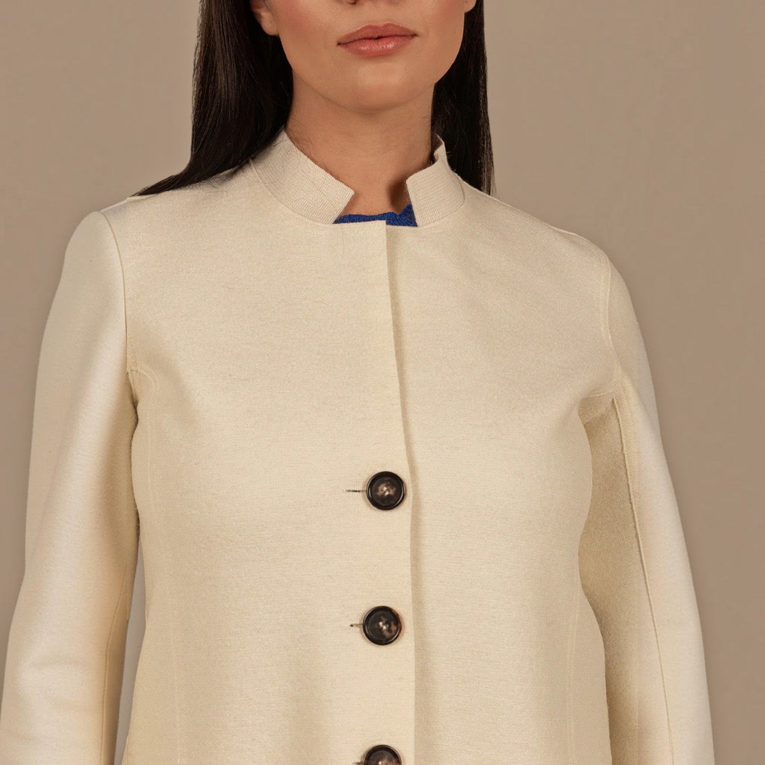 Close up of Kuna Ibis ivory coat featuring showing collar, buttons and concealed front panel.