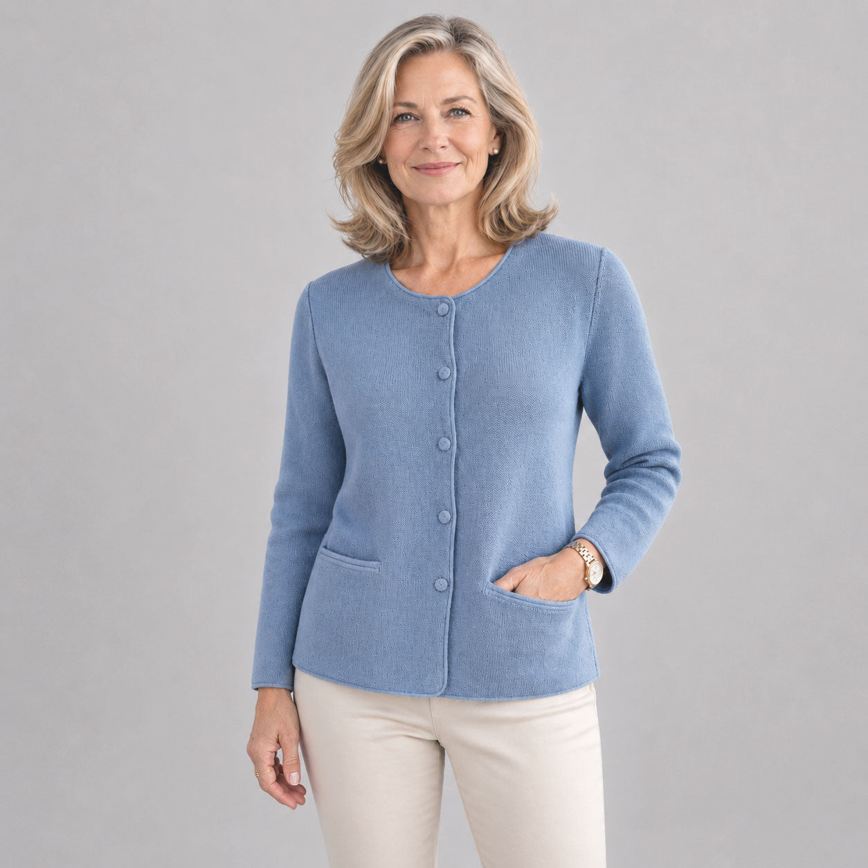Lady wearing classic buttoned alpaca cardigan in soft blue, warm natural fibre knitwear.
