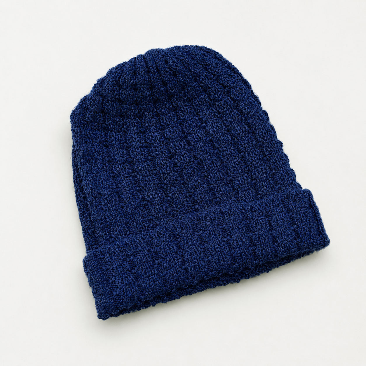 Blue knitted alpaca beanie on a white background