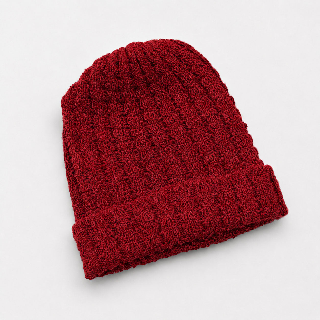 Red knitted alpaca beanie on a light gray background
