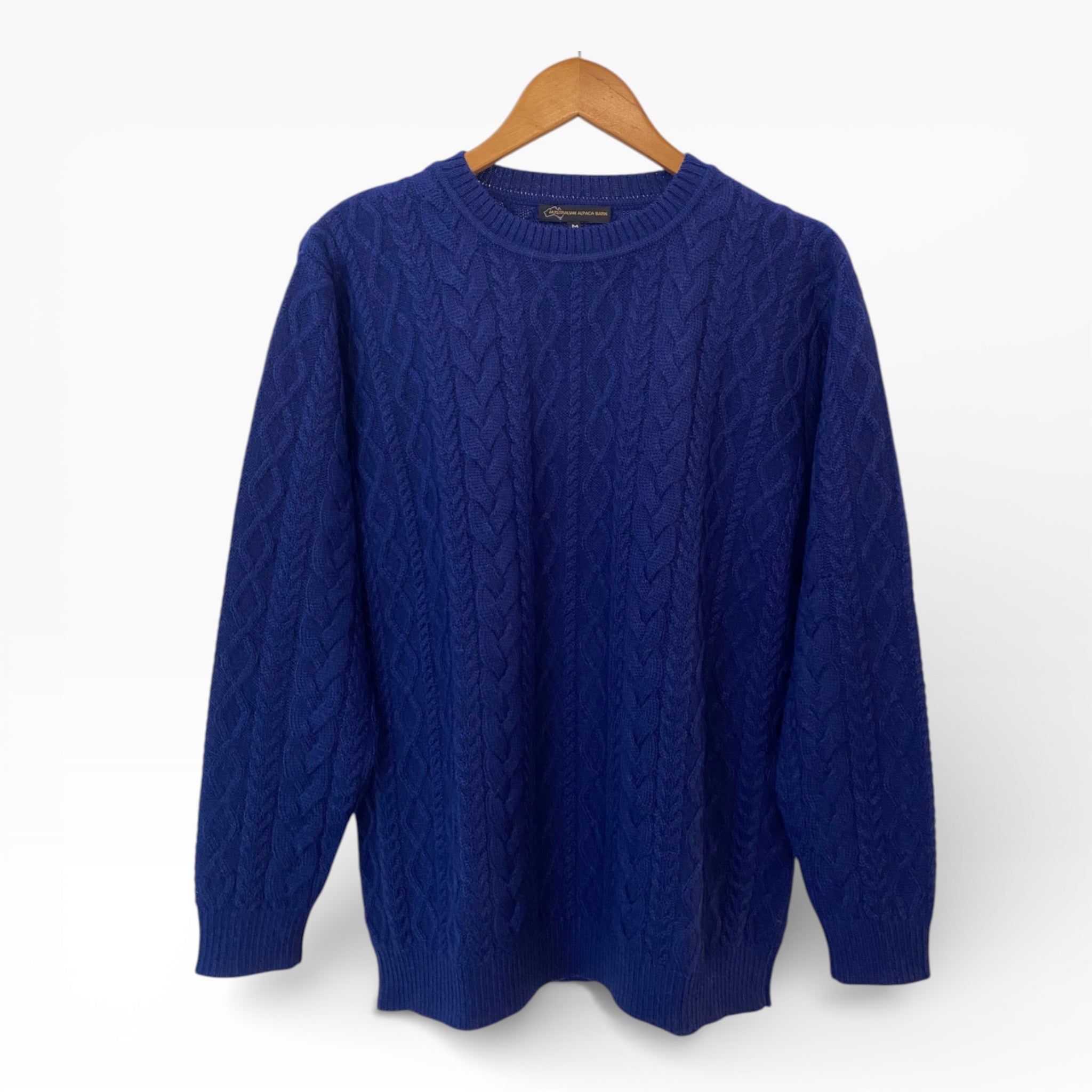 Blue Men's cable sweater on a hanger against a white background