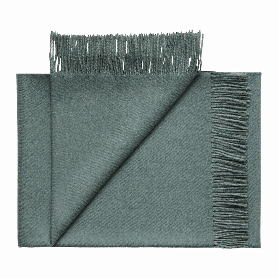 Folded alpaca throw rug showing soft woven texture, Green with fringes