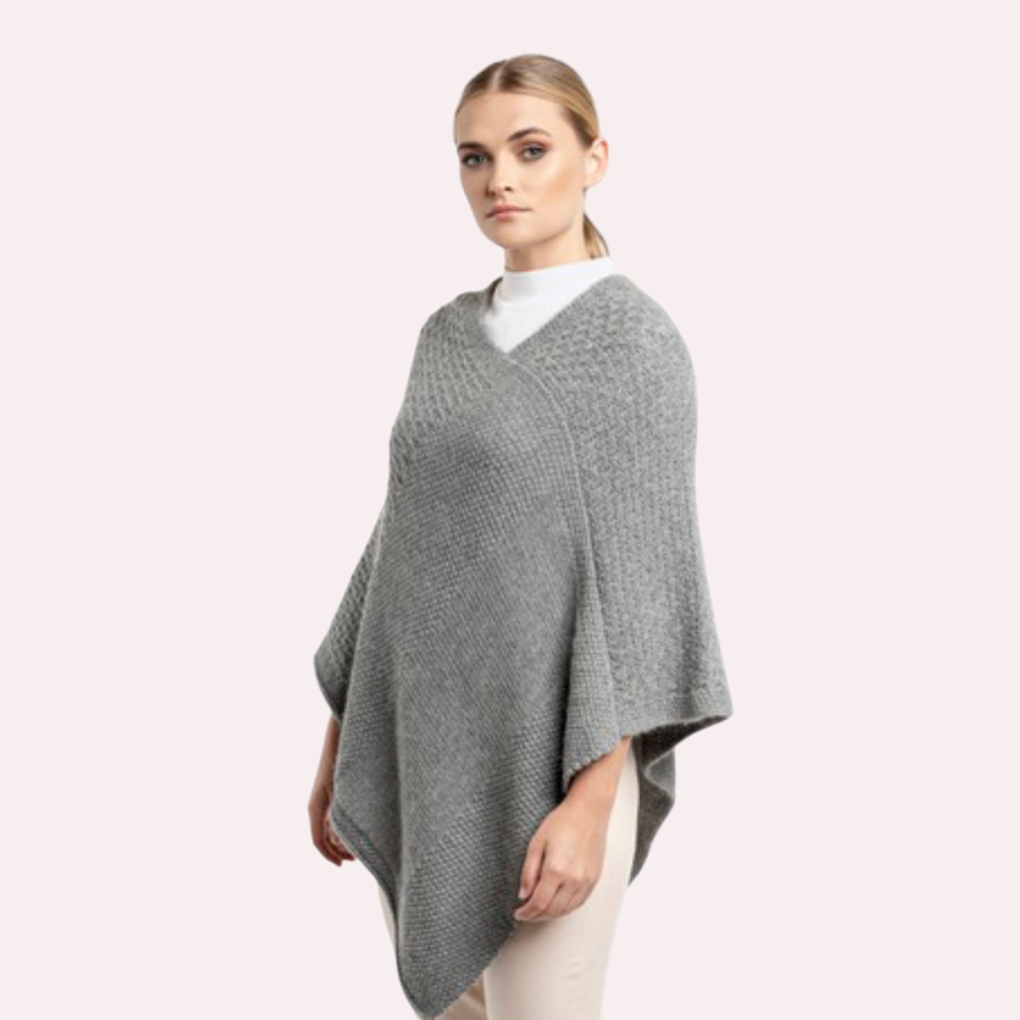 Model wearing soft grey alpaca knit poncho, styled as a warm winter layer.