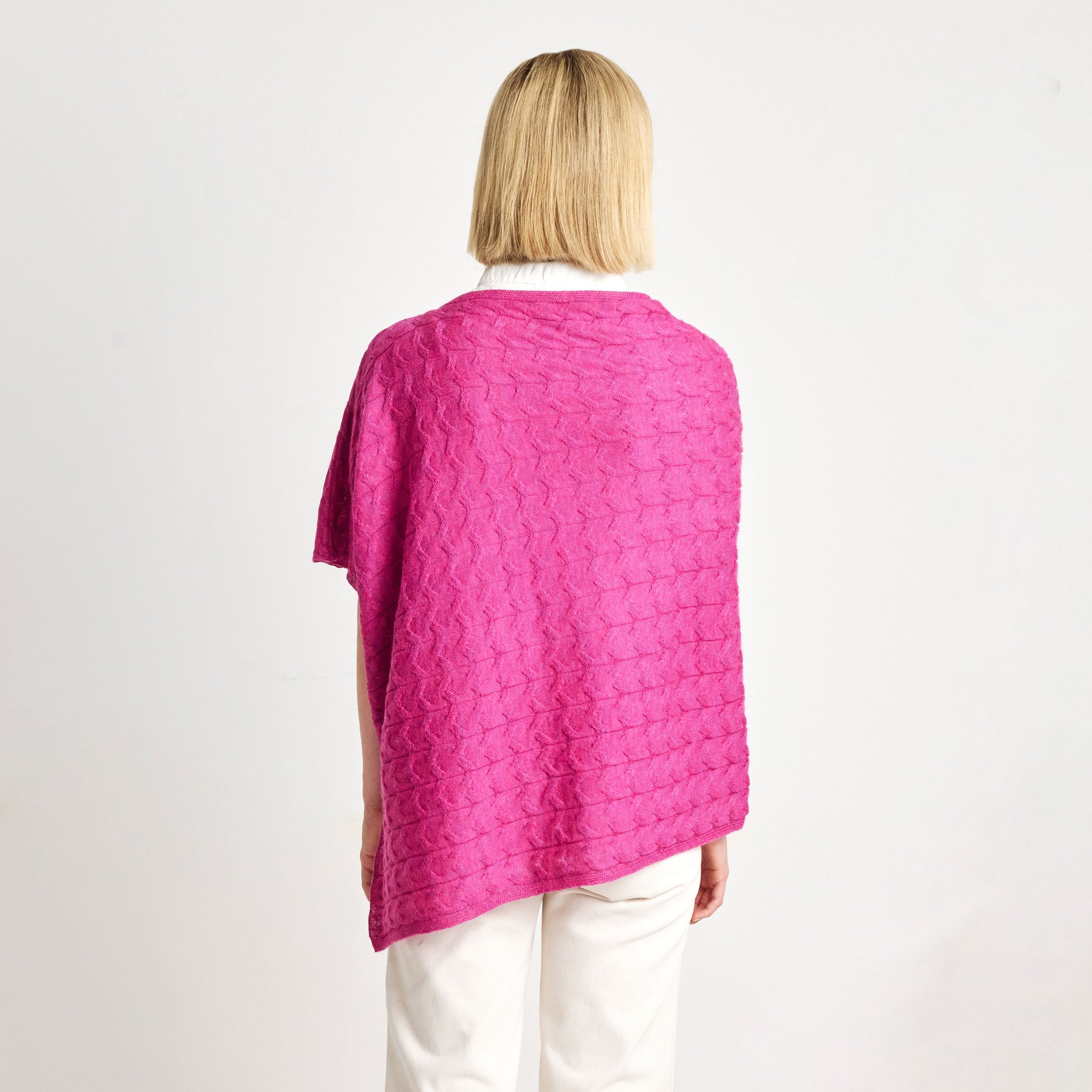 Women’s pink Baby Alpaca poncho styled with white trousers