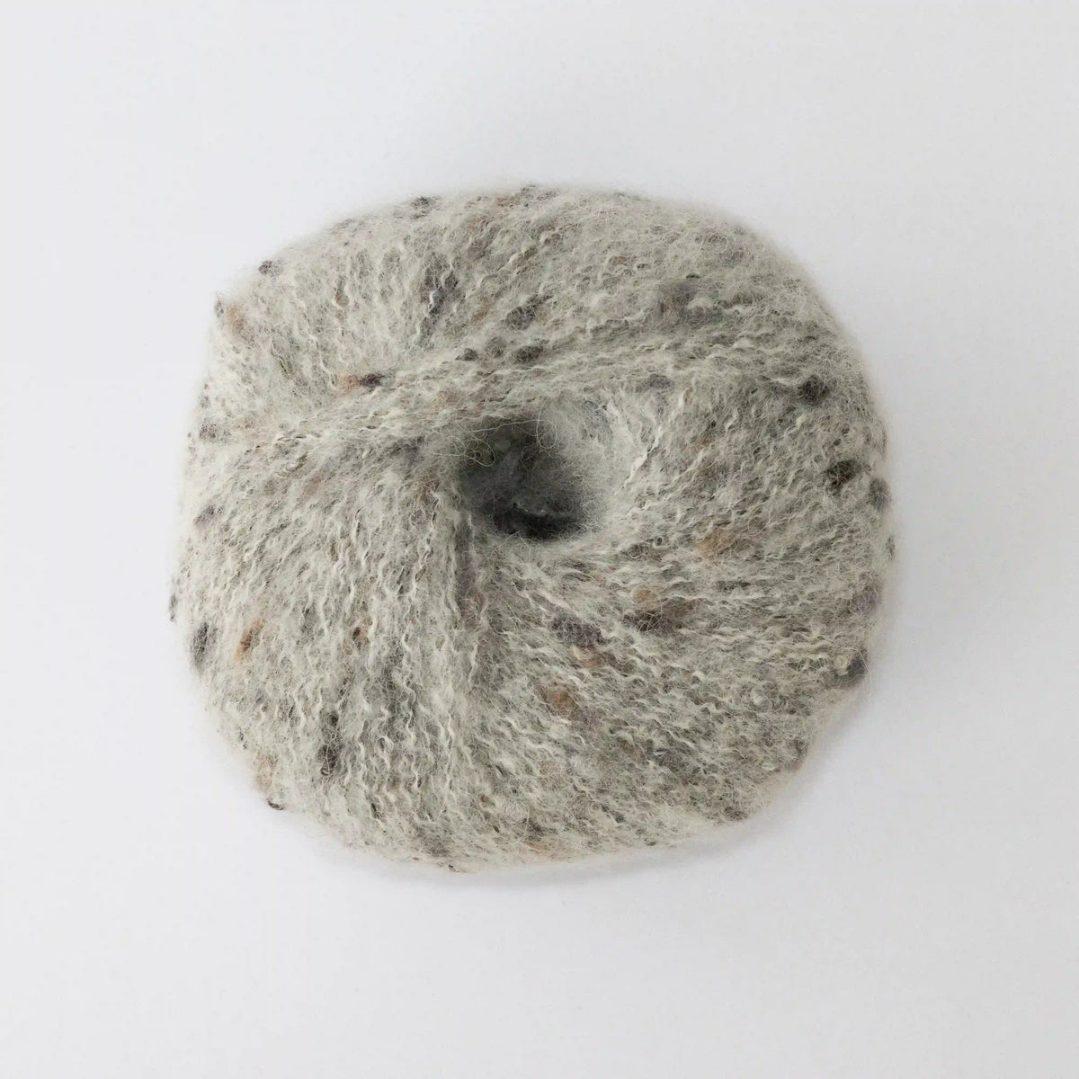 Overhead view of Silverwhite Indulge baby alpaca bouclé yarn without a label.
