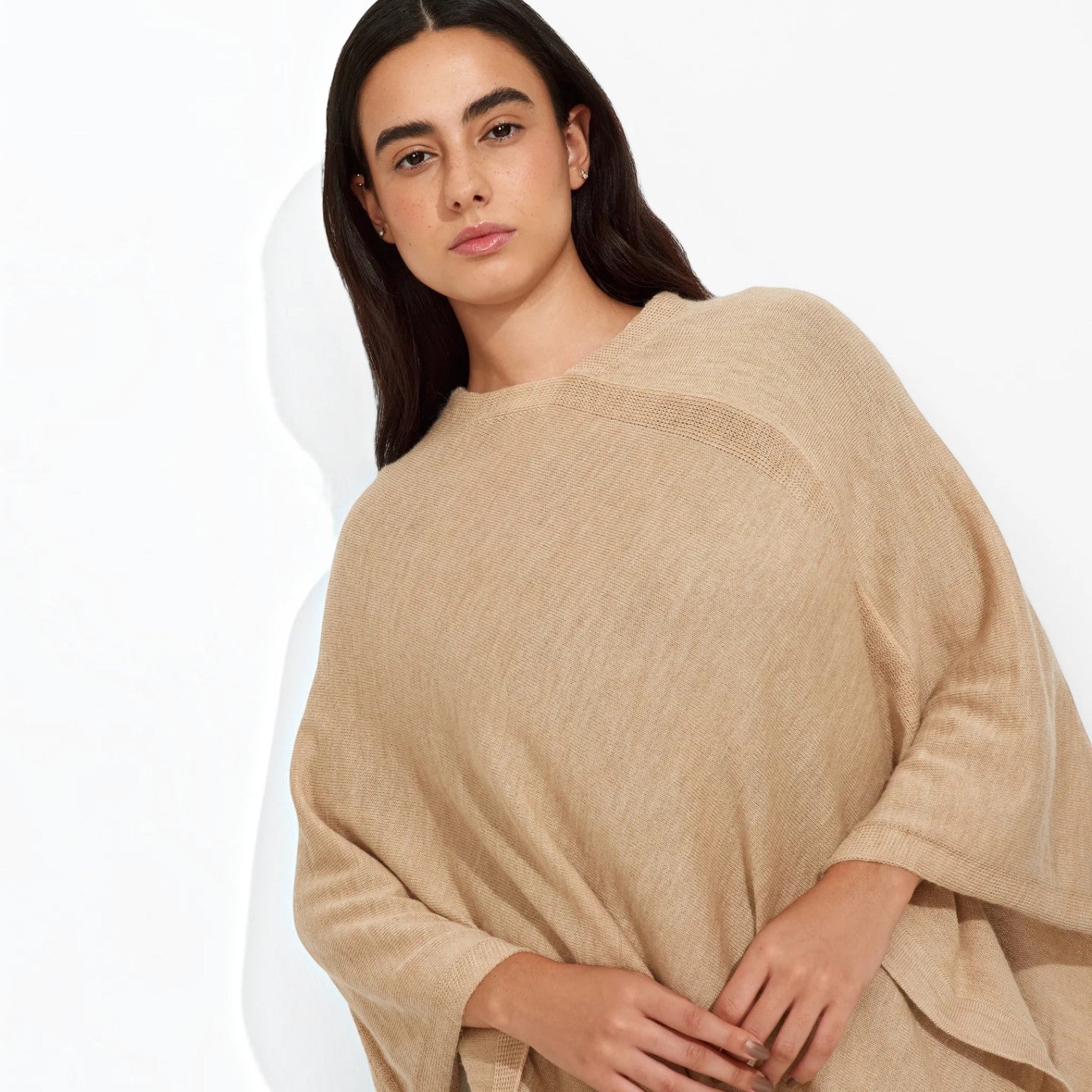 Female model wearing the Almendra sand-coloured alpaca poncho