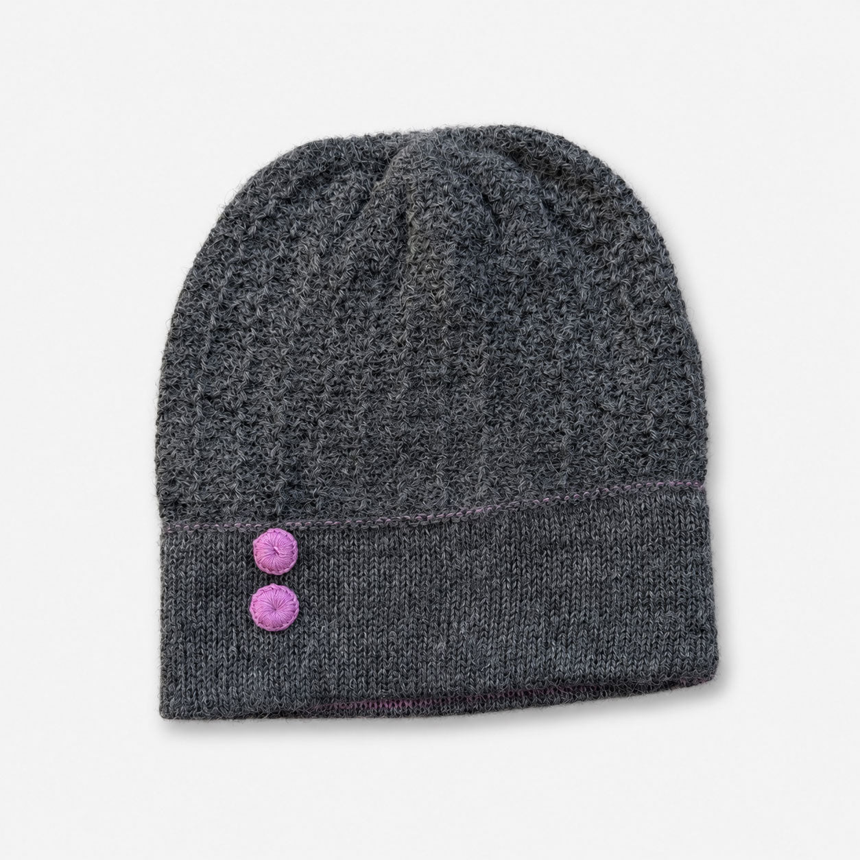 Gray knit alpaca beanie with pink buttons on a light gray background