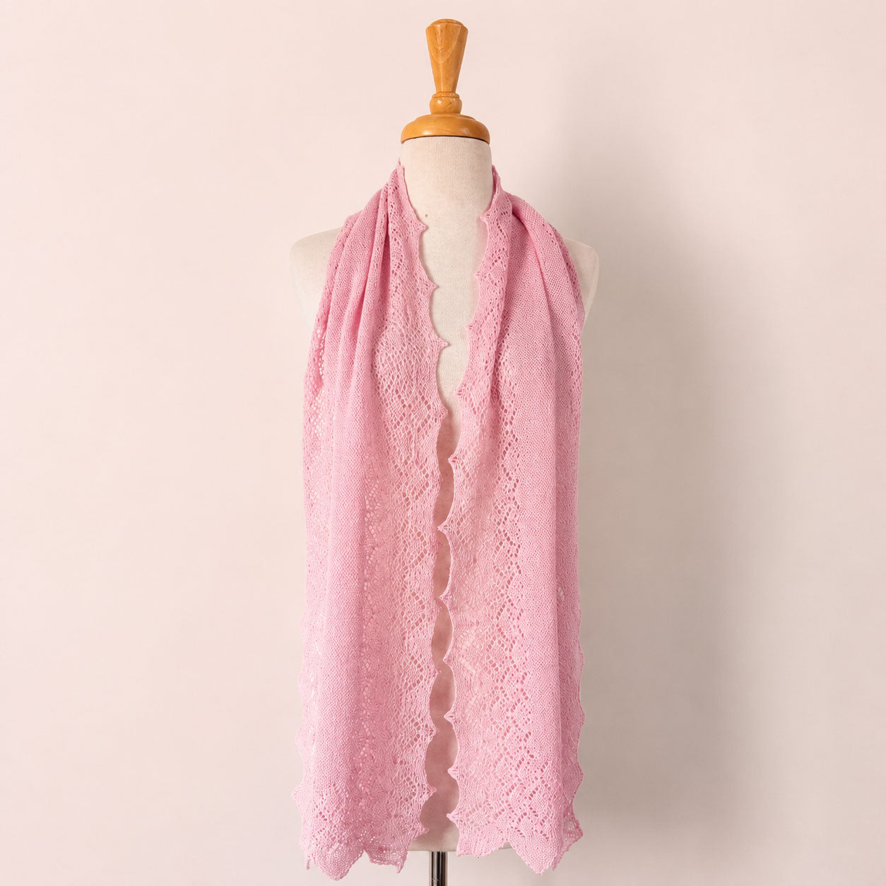 Pale pink baby alpaca lace scarf displayed on a mannequin with a soft, feminine lace knit design