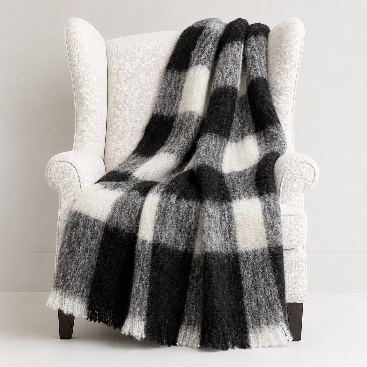 Black and white checkered brushed alpaca blanket draped over a white armchair.
