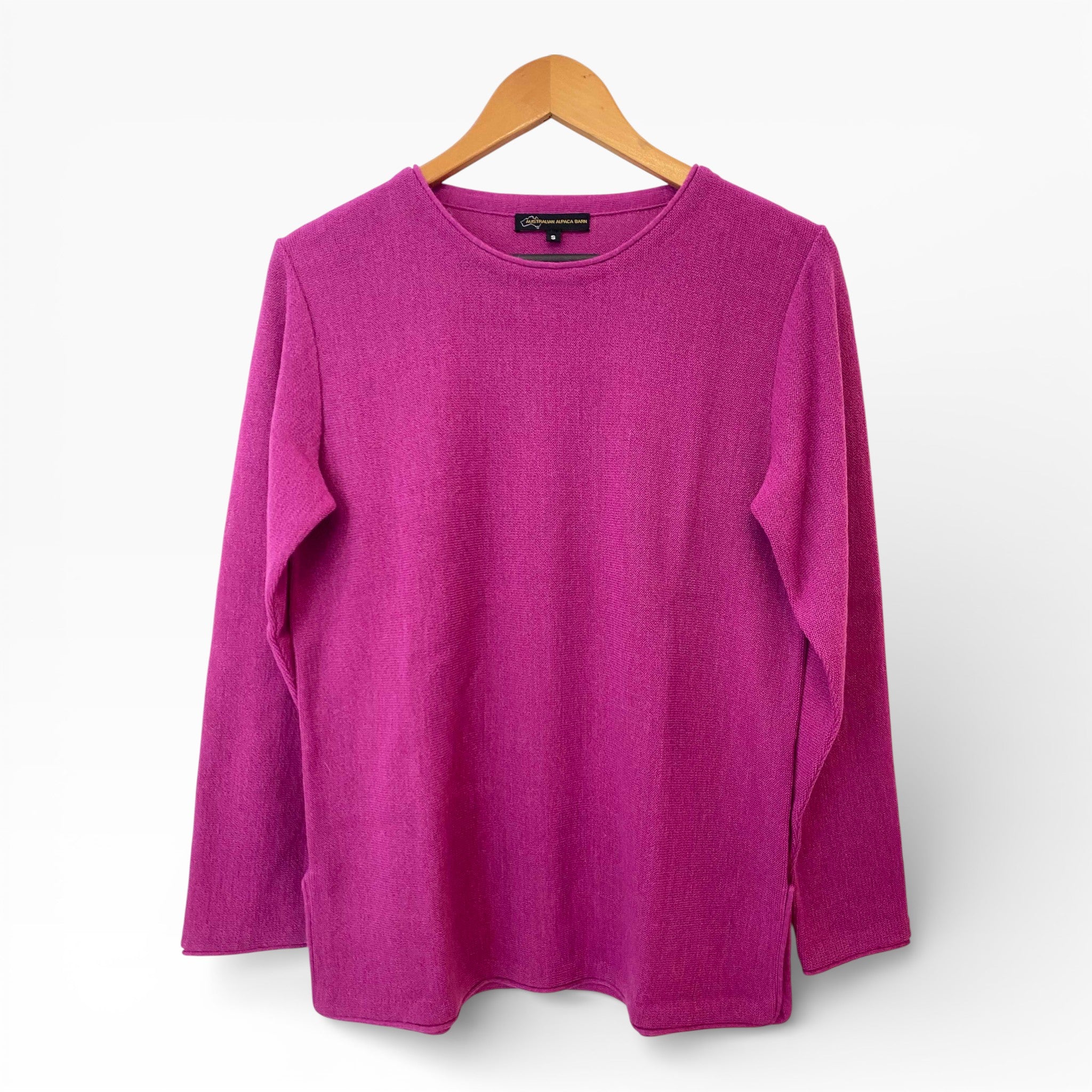 Pink sweater on a wooden hanger against a white background