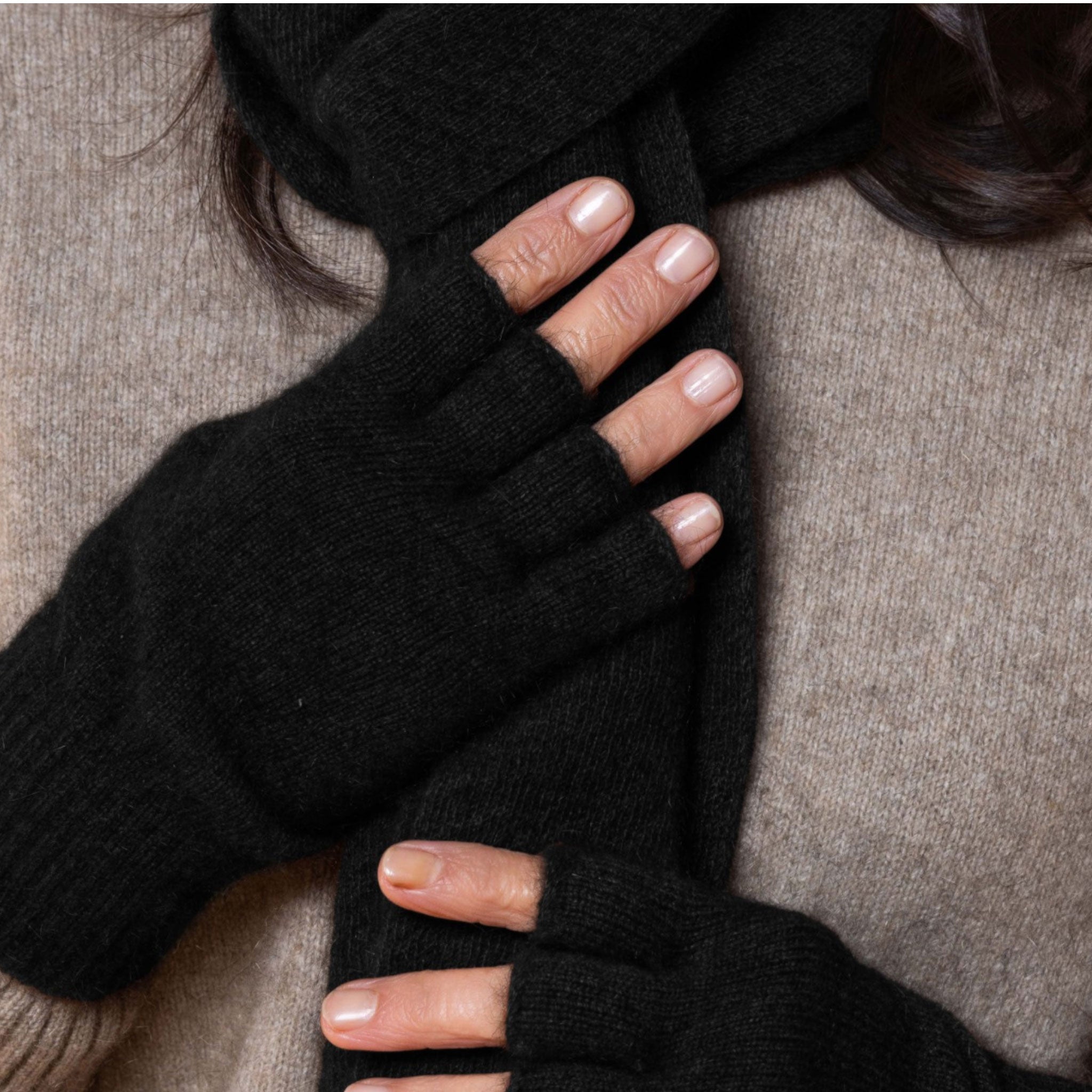 Person wearing black possum gloves with a neutral background