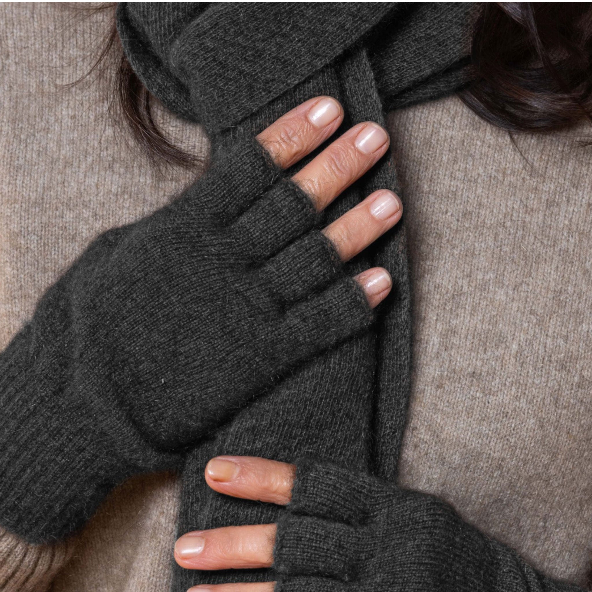 Person wearing dark gray possum fingerless gloves on a neutral background