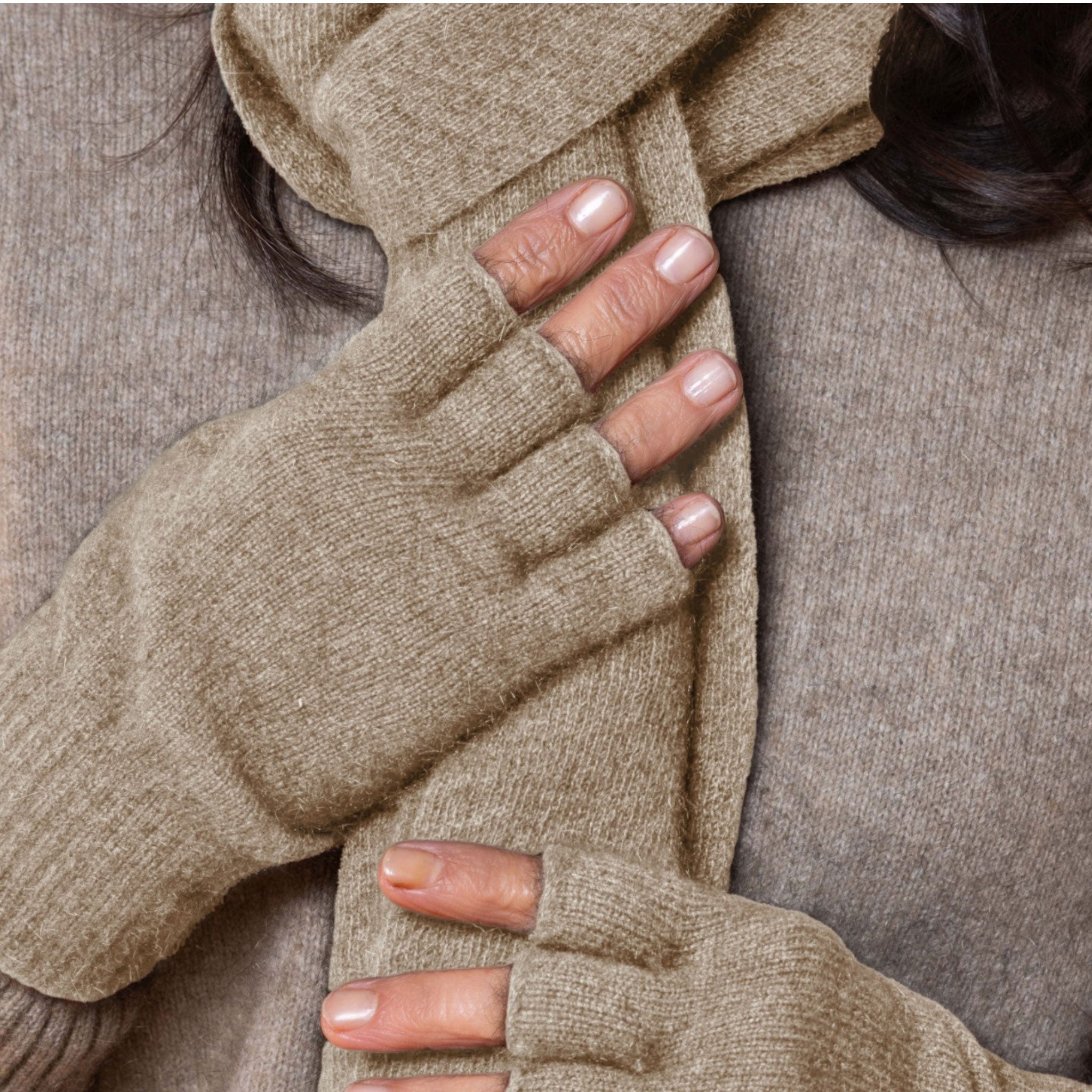 Close-up of a person wearing beige fingerless possum gloves and a matching scarf.