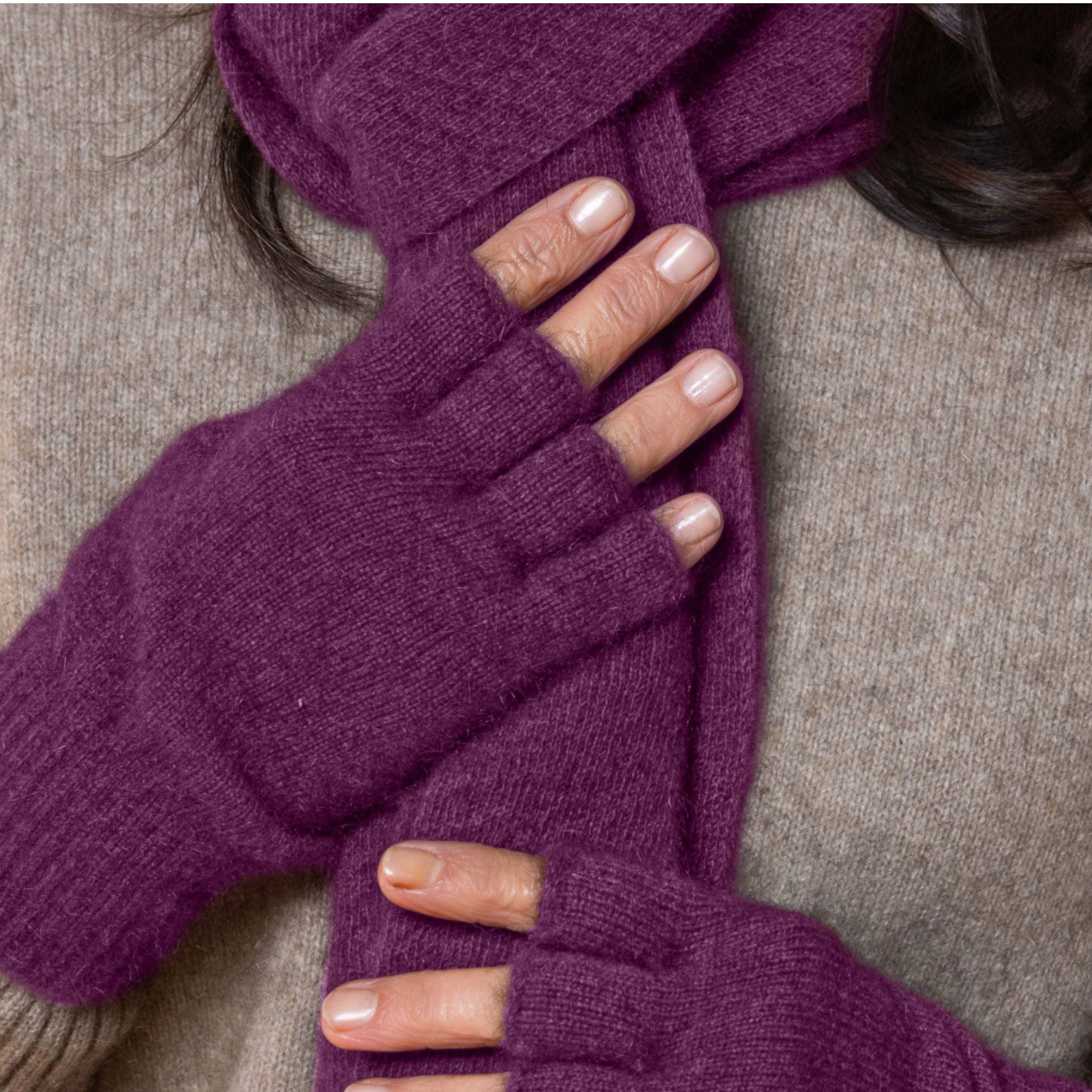 Purple fingerless possum gloves worn by a person on a neutral background