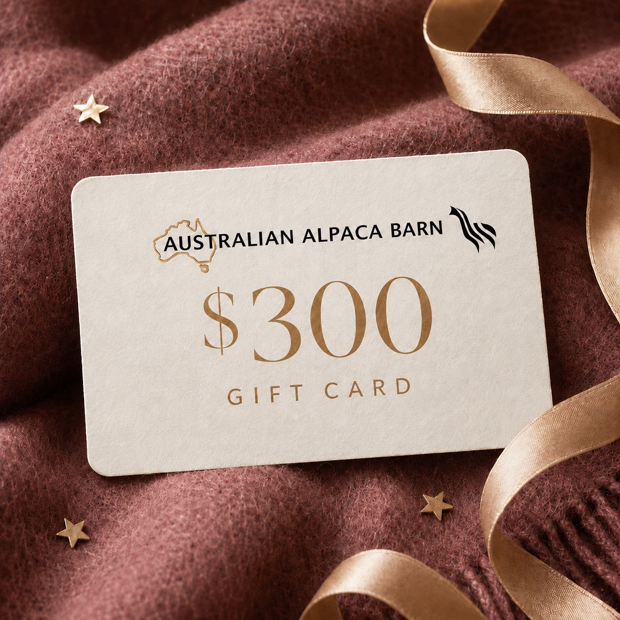 Australian Alpaca Barn $300 gift card presented on berry alpaca fabric with an ivory card, champagne ribbon and gold stars