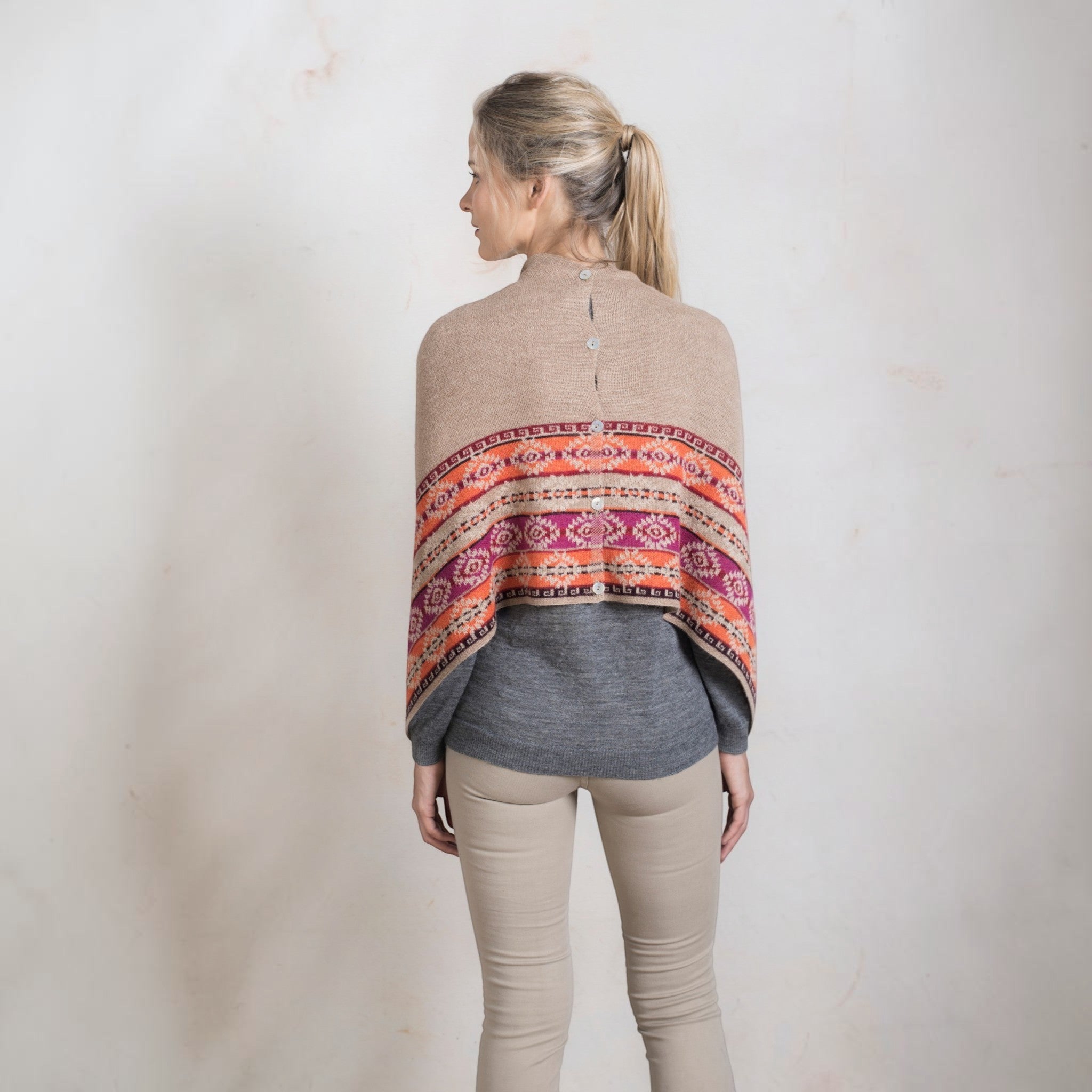 Woman wearing natural alpaca shawl with buttons as a cosy winter wrap.