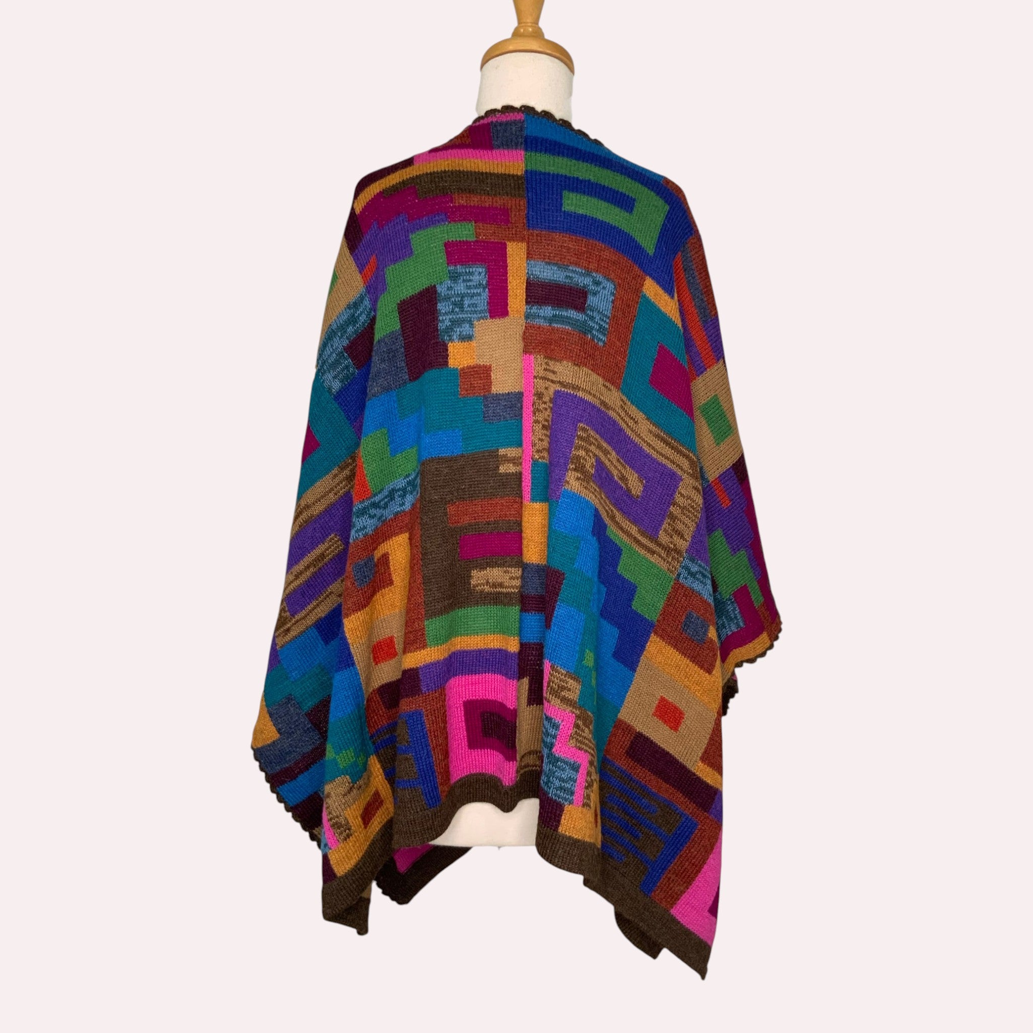 Colourful geometric-patterned Cape on a mannequin, warm breathable winter outerwear.