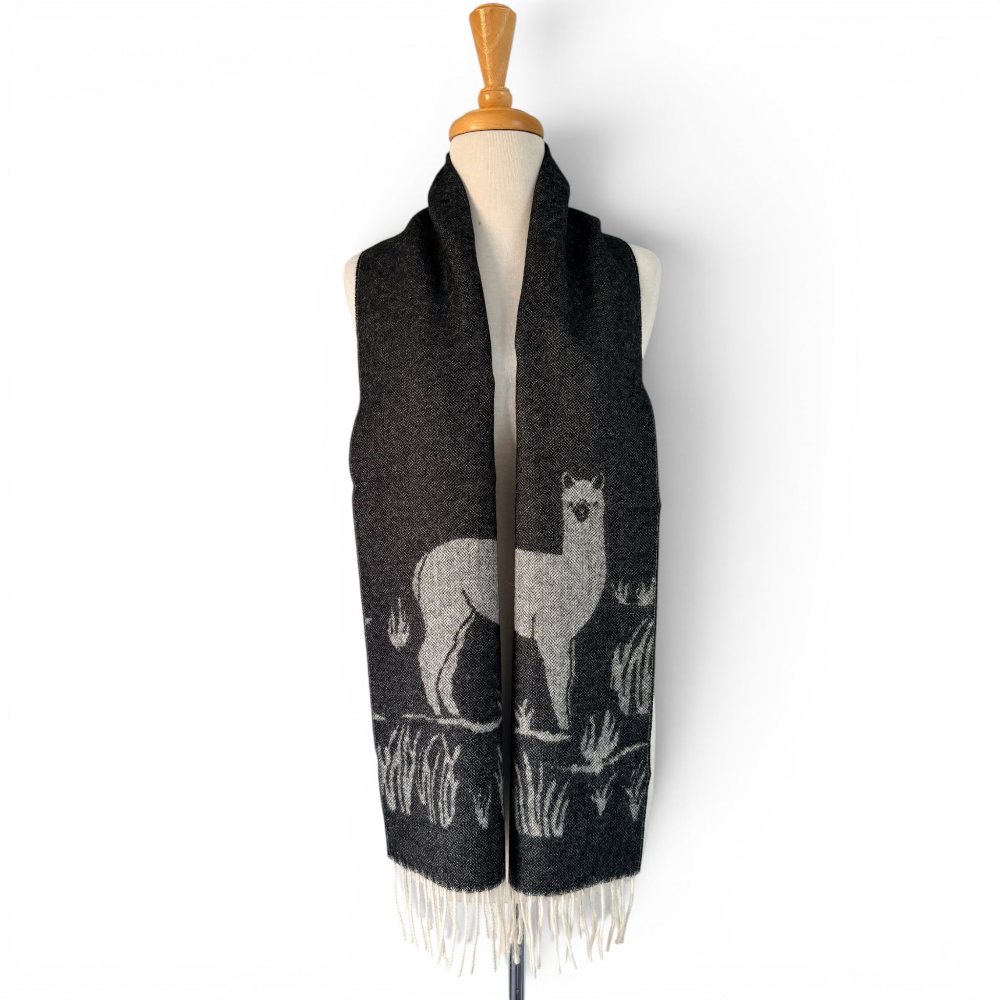 Black and white jacquard alpaca scarf with decorative llama-style pattern and soft fringe