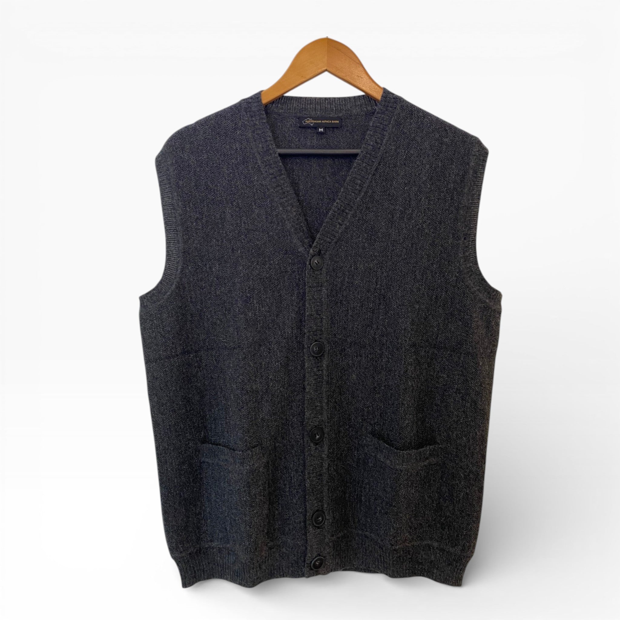 Dark gray vest with buttons on a wooden hanger against a white background
