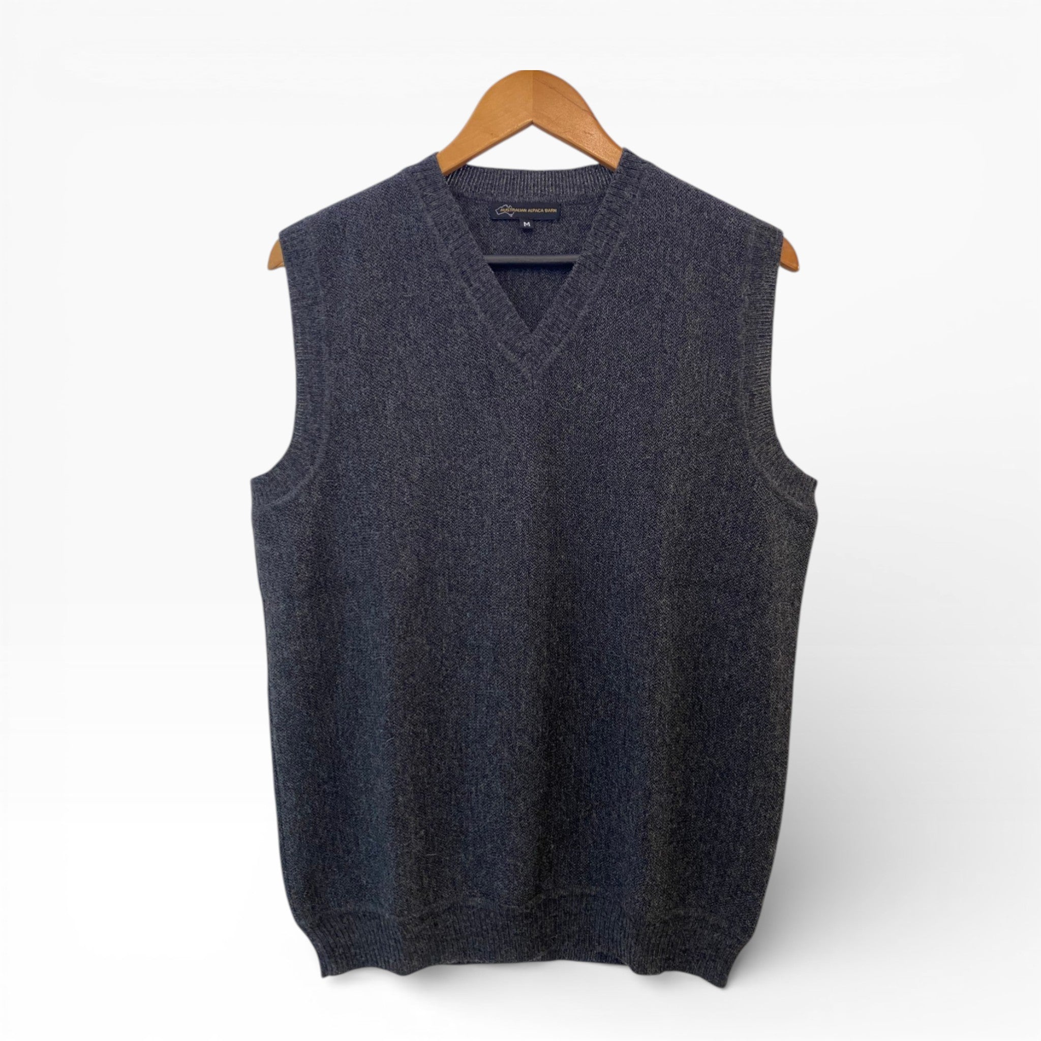 Dark gray sleeveless sweater vest on a wooden hanger against a white background