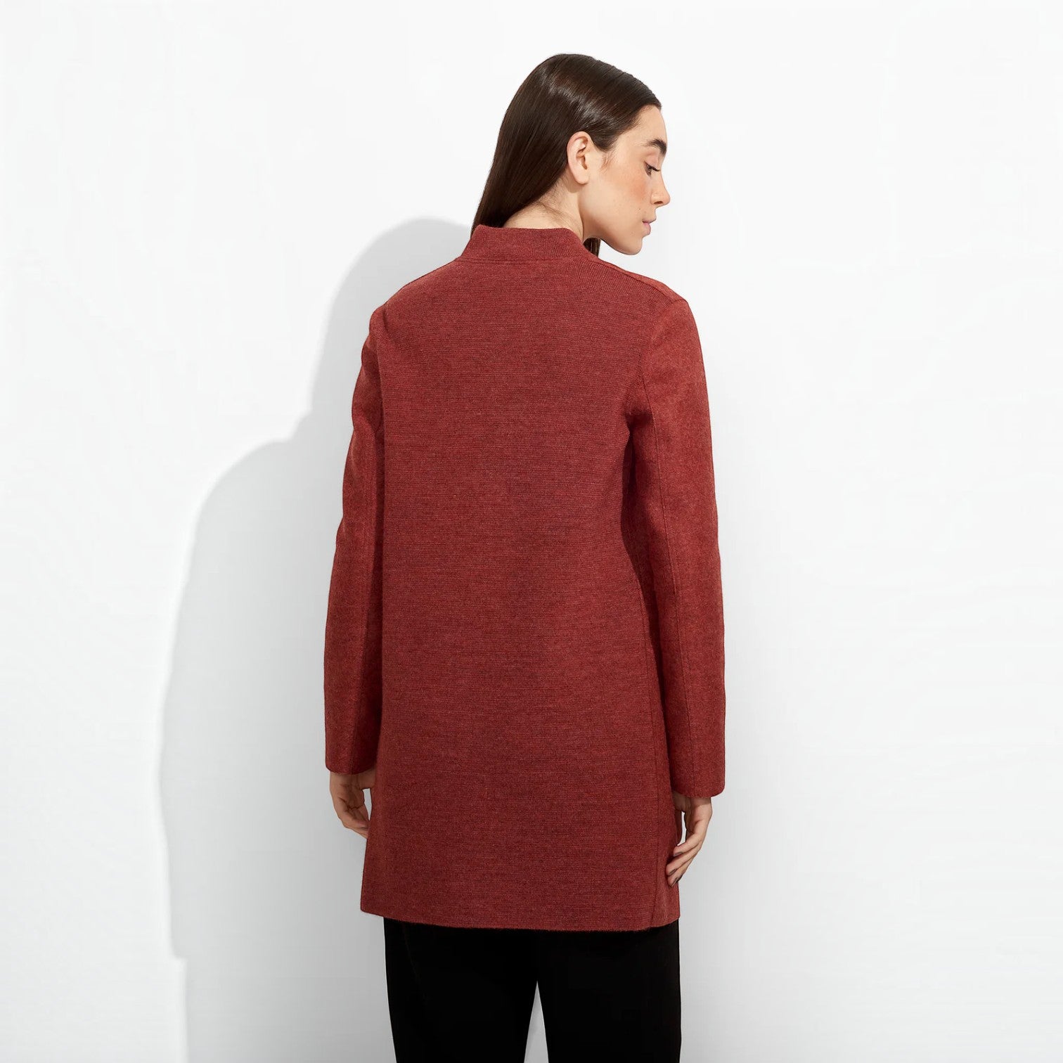 Women’s warm red knee-length coat styled with black trousers