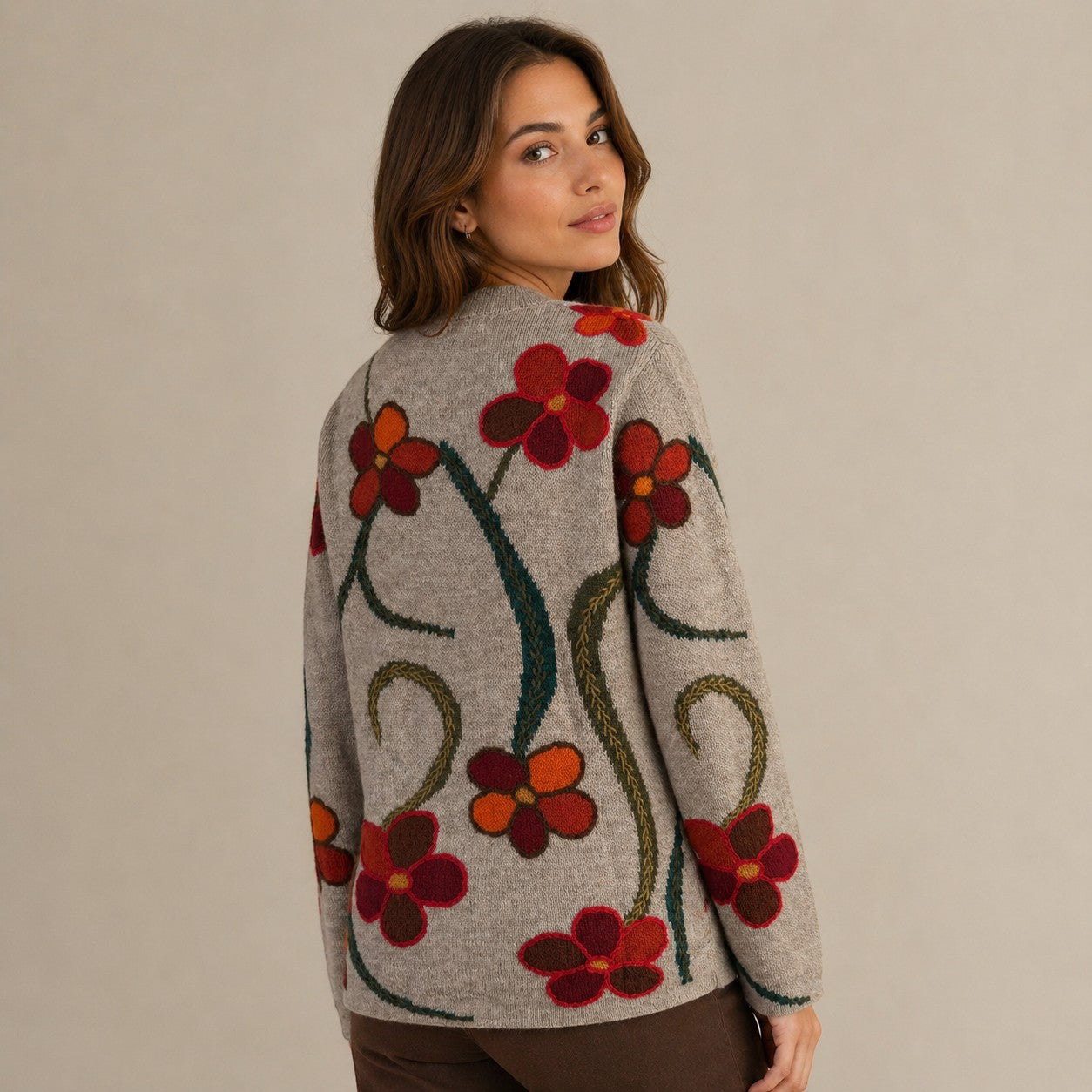 Woman wearing a warm alpaca intarsia cardigan with floral patterns on a beige background