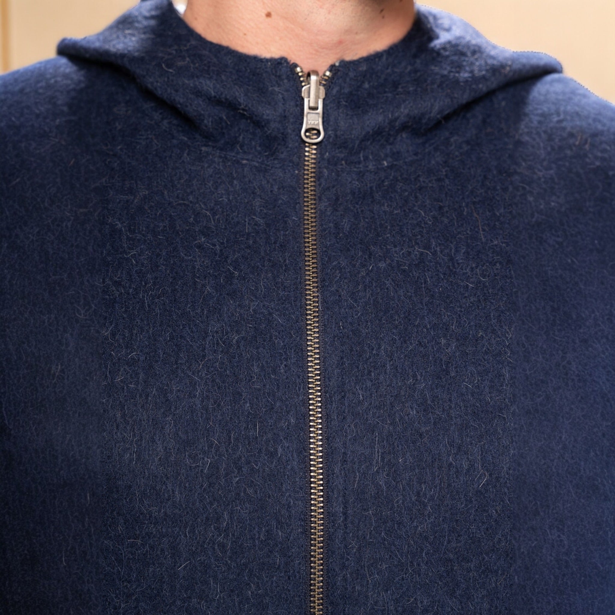 Close-up of zip detail on men’s reversible alpaca hooded jacket.