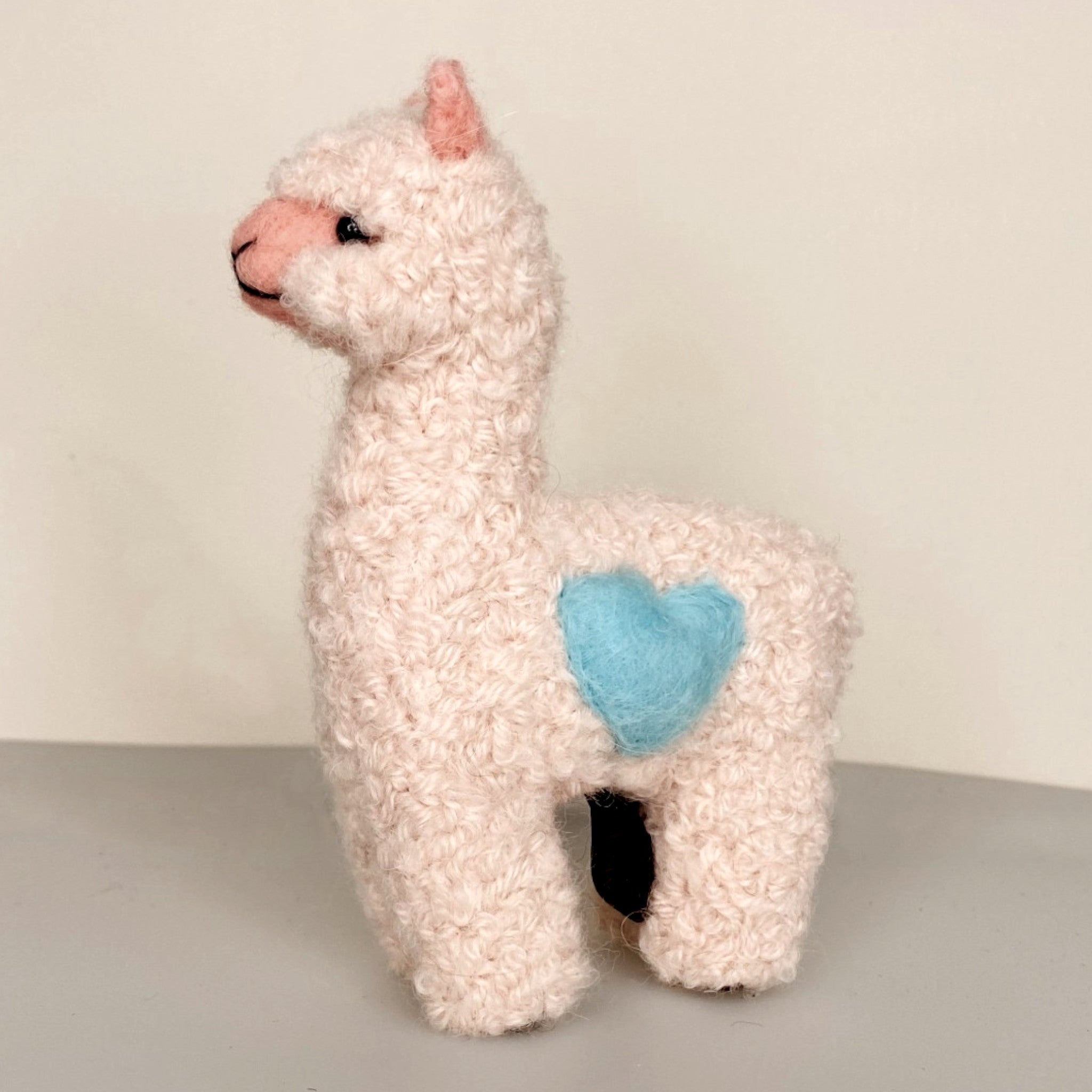 Needle felted alpaca Pink with blue heart, showing soft fibre and cute face.