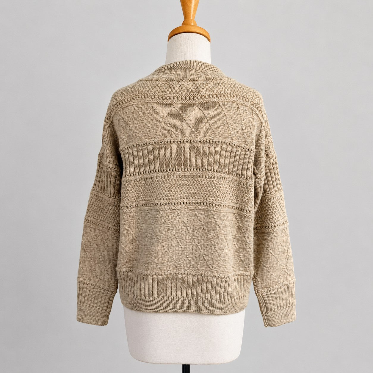 Women’s camel alpaca sweater with high neck and cable knit detail.
