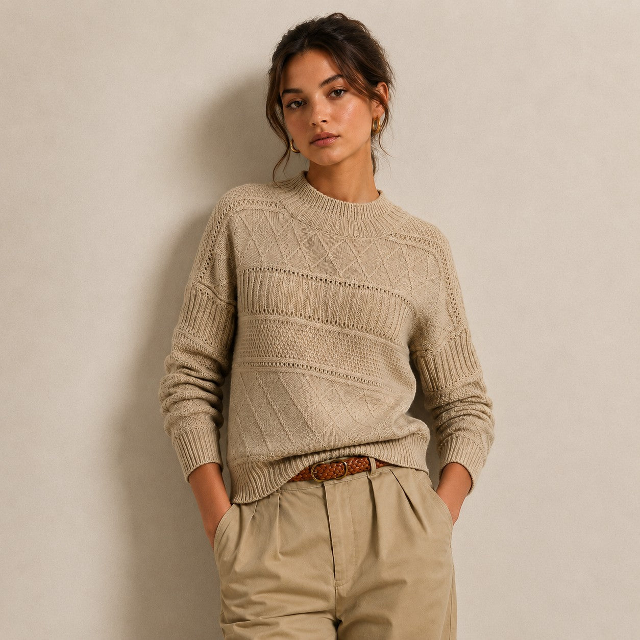 Woman wearing camel alpaca high neck sweater with cable knit detail.