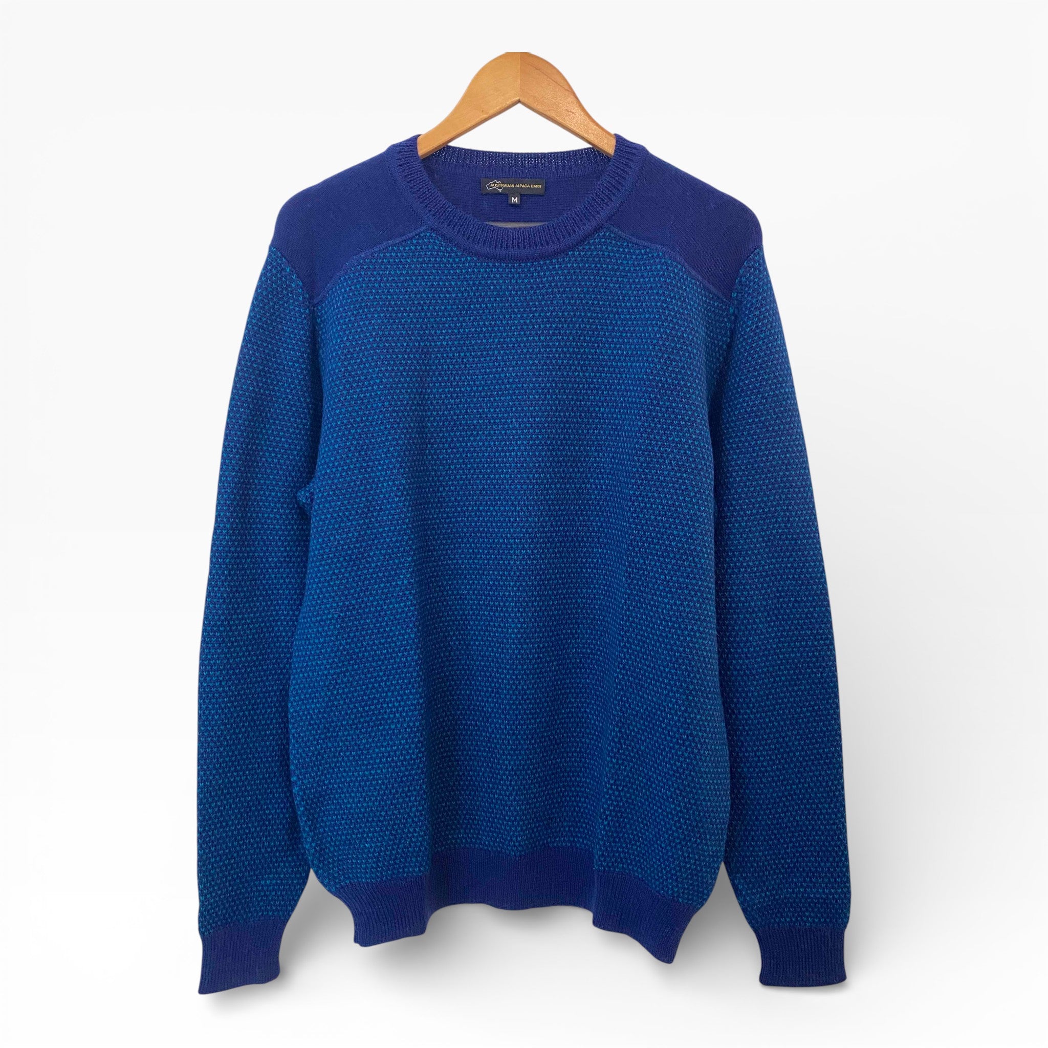 Blue sweater on a wooden hanger against a white background