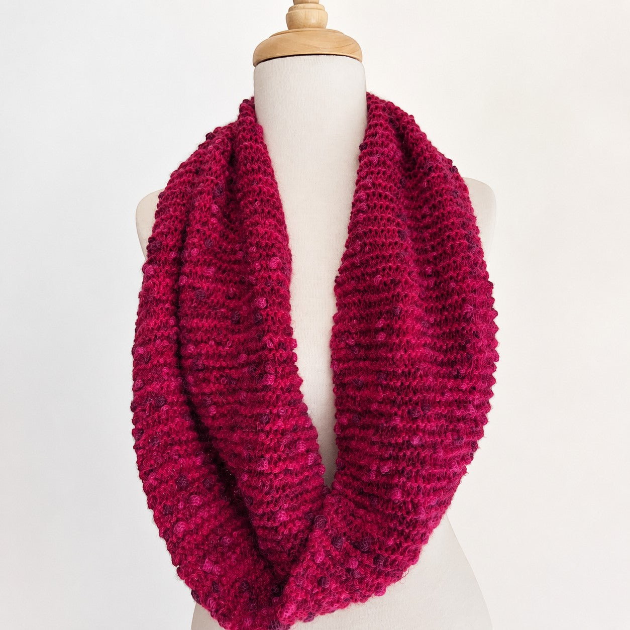Hand-knitted fuchsia Baby Alpaca PomPom snood displayed on a mannequin