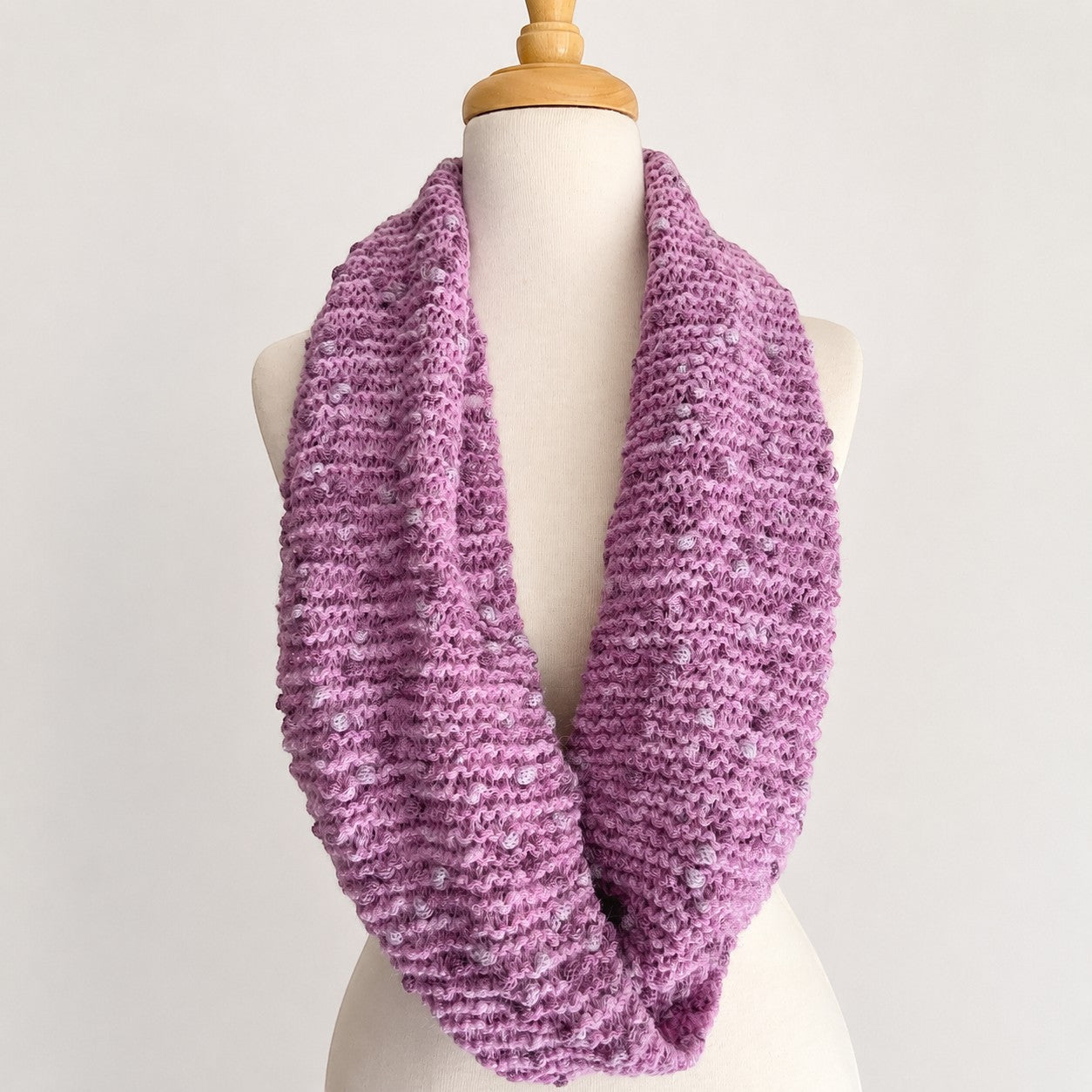 Hand-knitted pink Baby Alpaca PomPom snood displayed on a mannequin