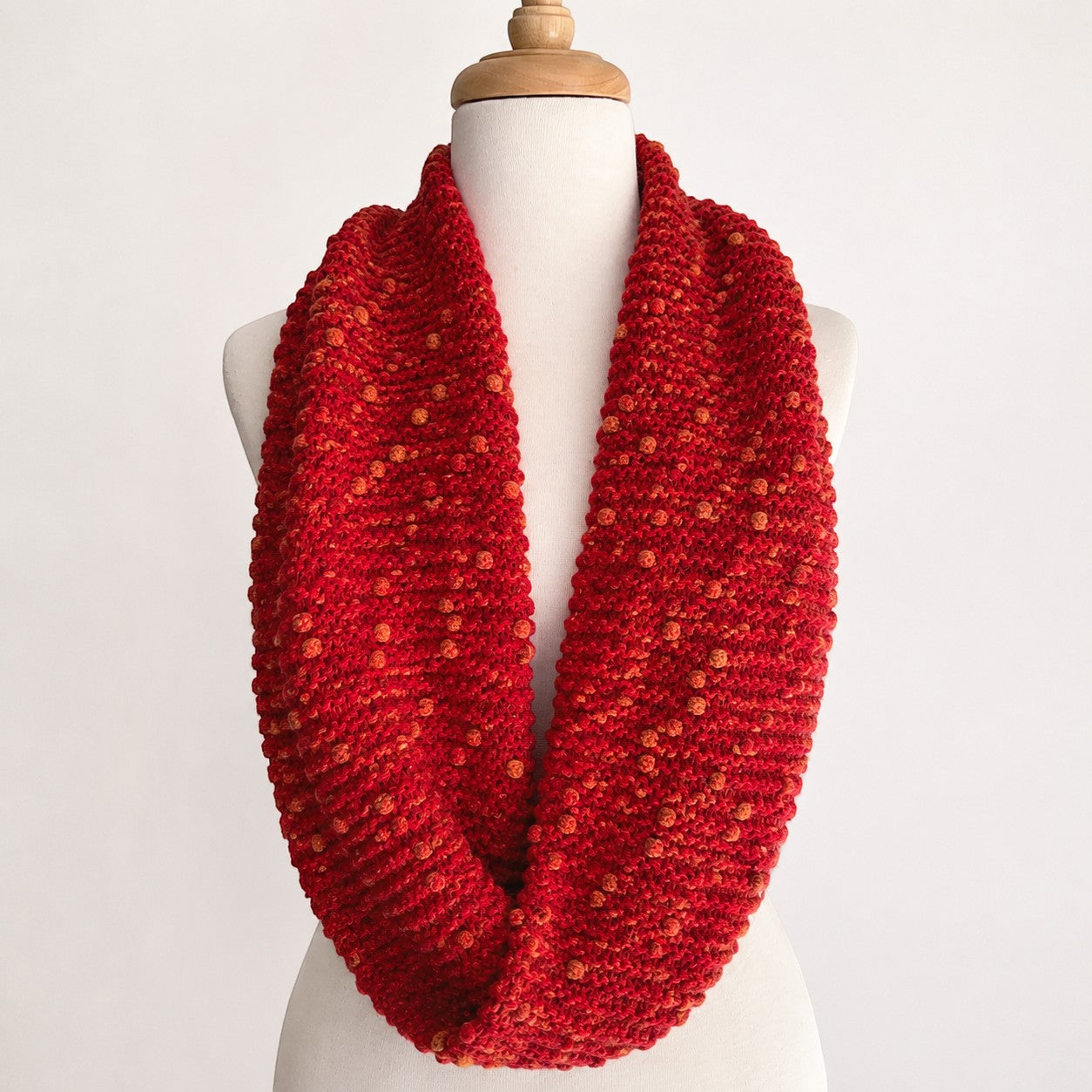 Textured red alpaca infinity scarf displayed on a mannequin