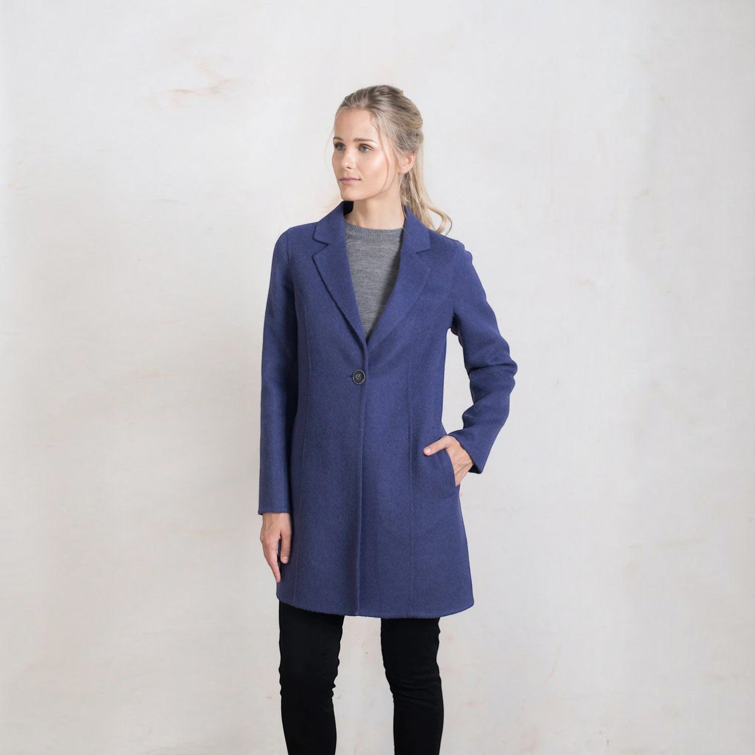 Full-length front view of the women’s blue alpaca coat styled with black trousers