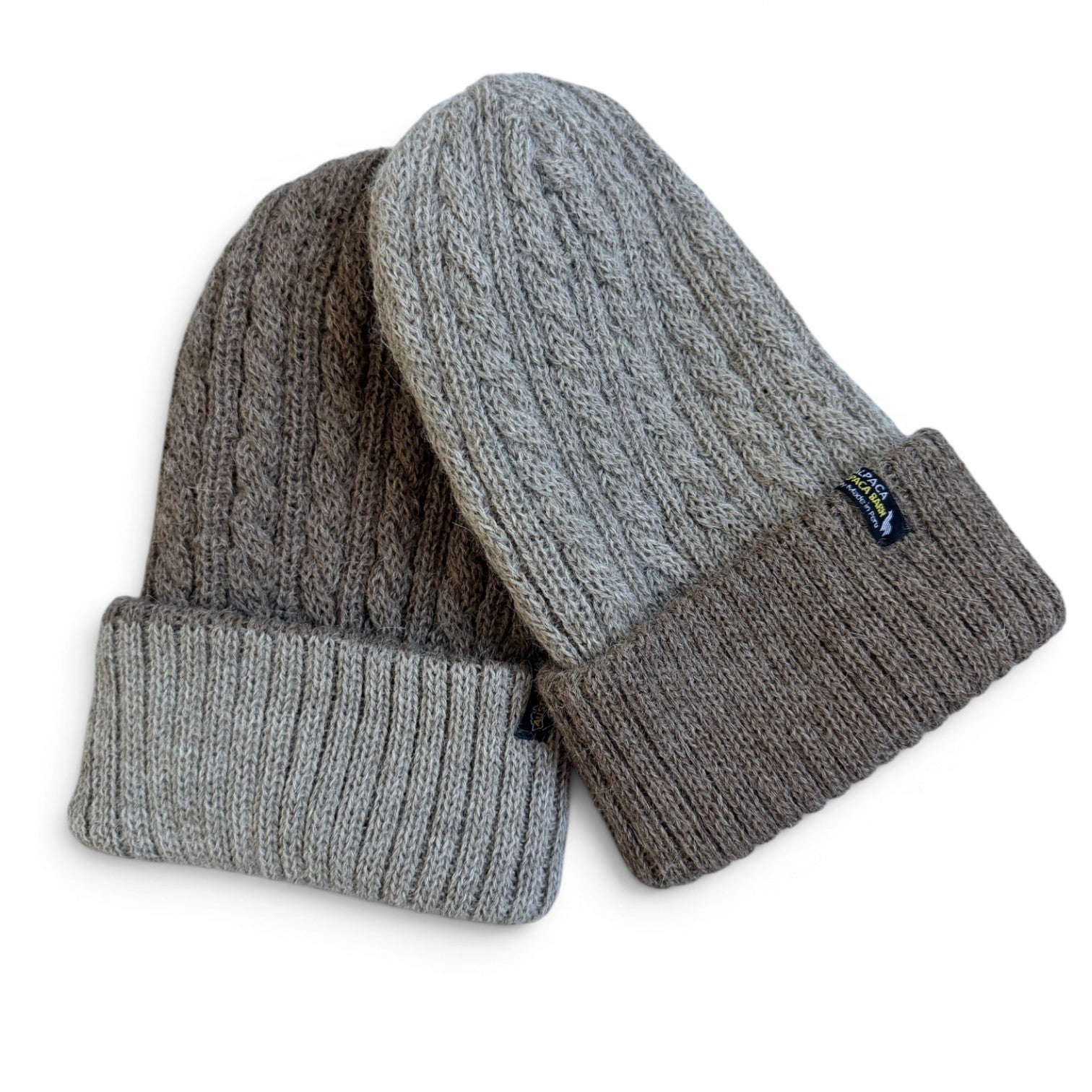 Two cable-knit Alpaca beanie hats in shades of gray, one heather gray and one charcoal gray, with ribbed cuffs, shown on a white background.