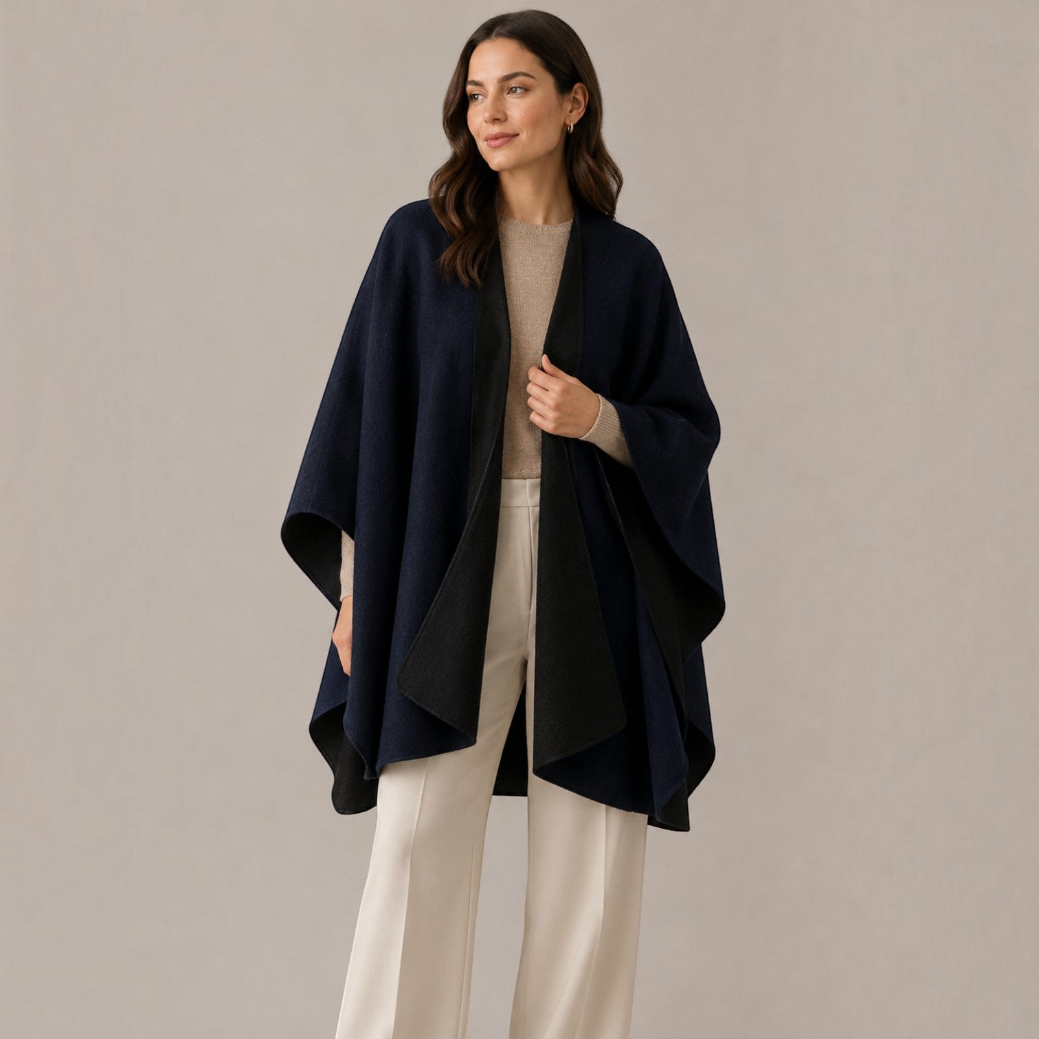 Woman wearing a navy and black reversible alpaca cape with a relaxed open-front design.
