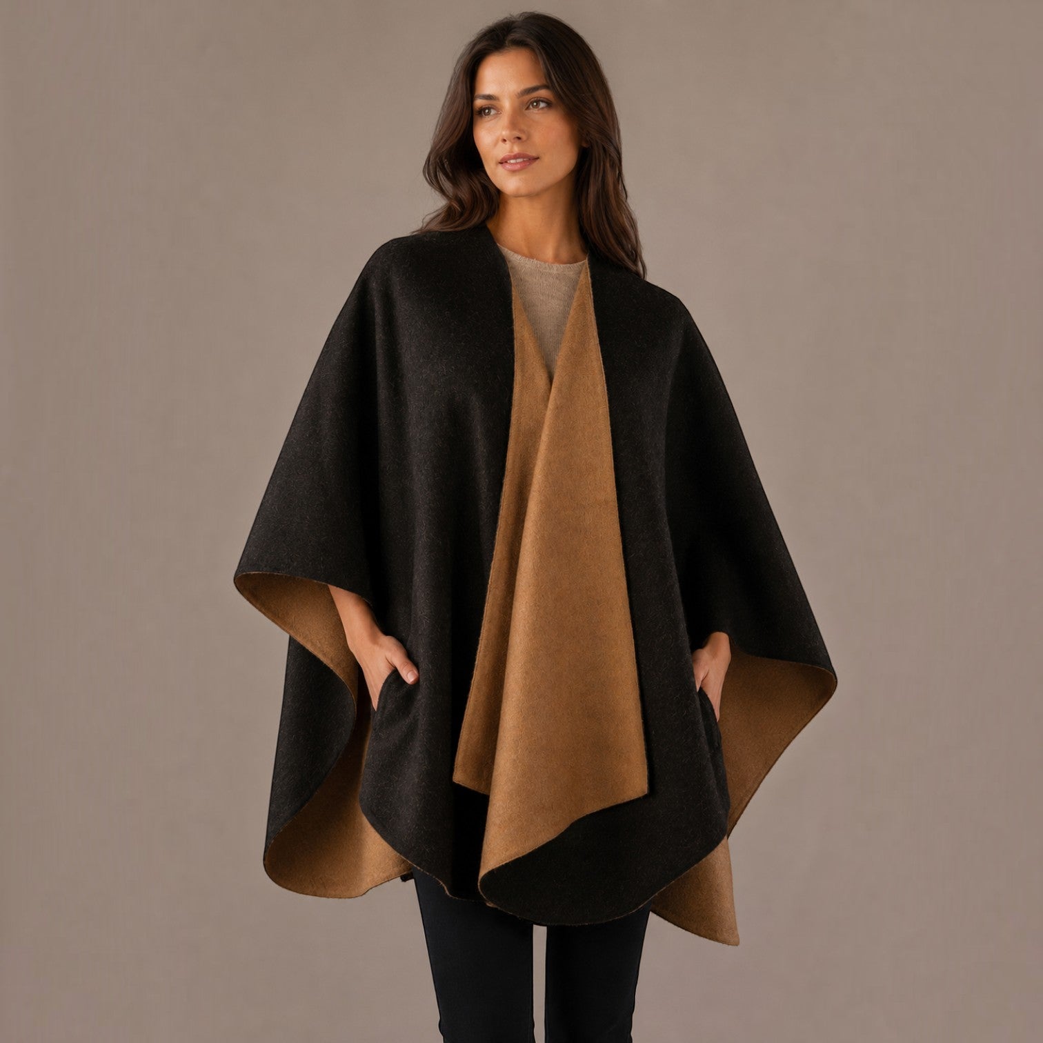 Woman wearing a black and camel reversible alpaca cape with a flowing open-front silhouette.