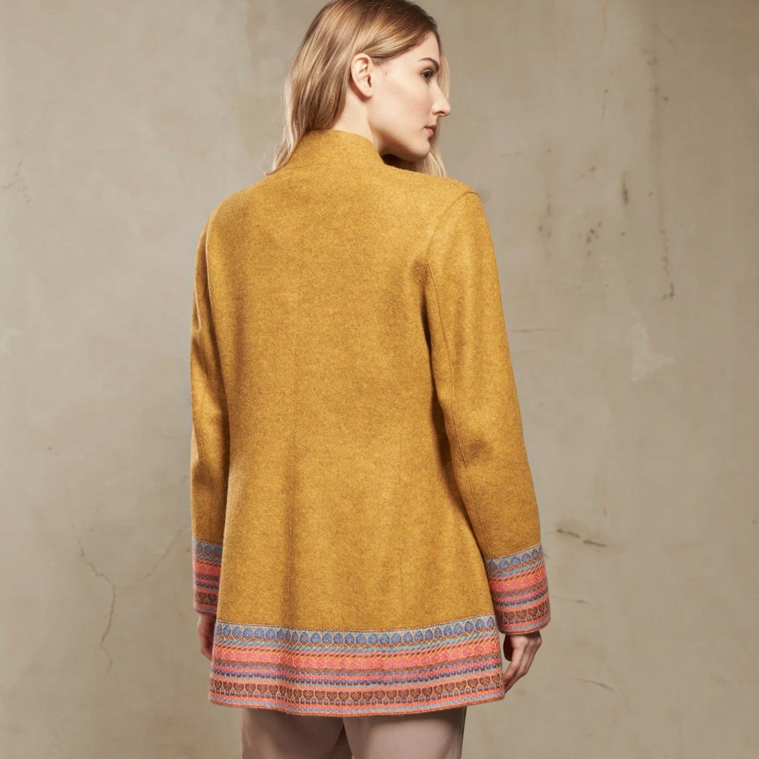 Back view of the mustard alpaca wool coat with colourful woven hem and cuff detailing